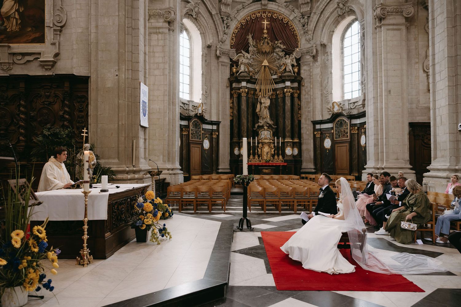 Wedding ceremony in a grand cathedral with ornate decorations and flower arrangements.
