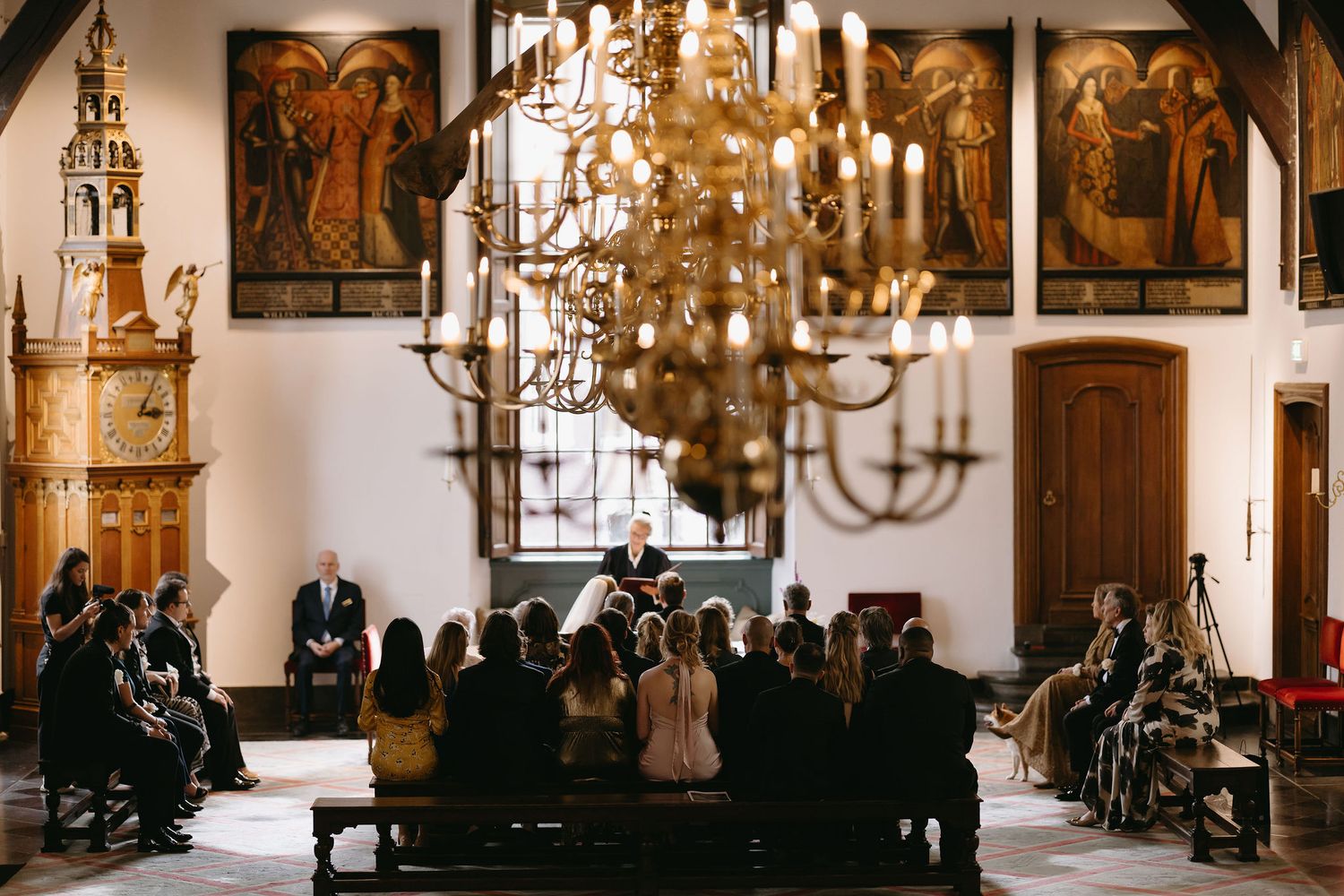 Church interior with grand chandeliers and religious artwork during a wedding ceremony.