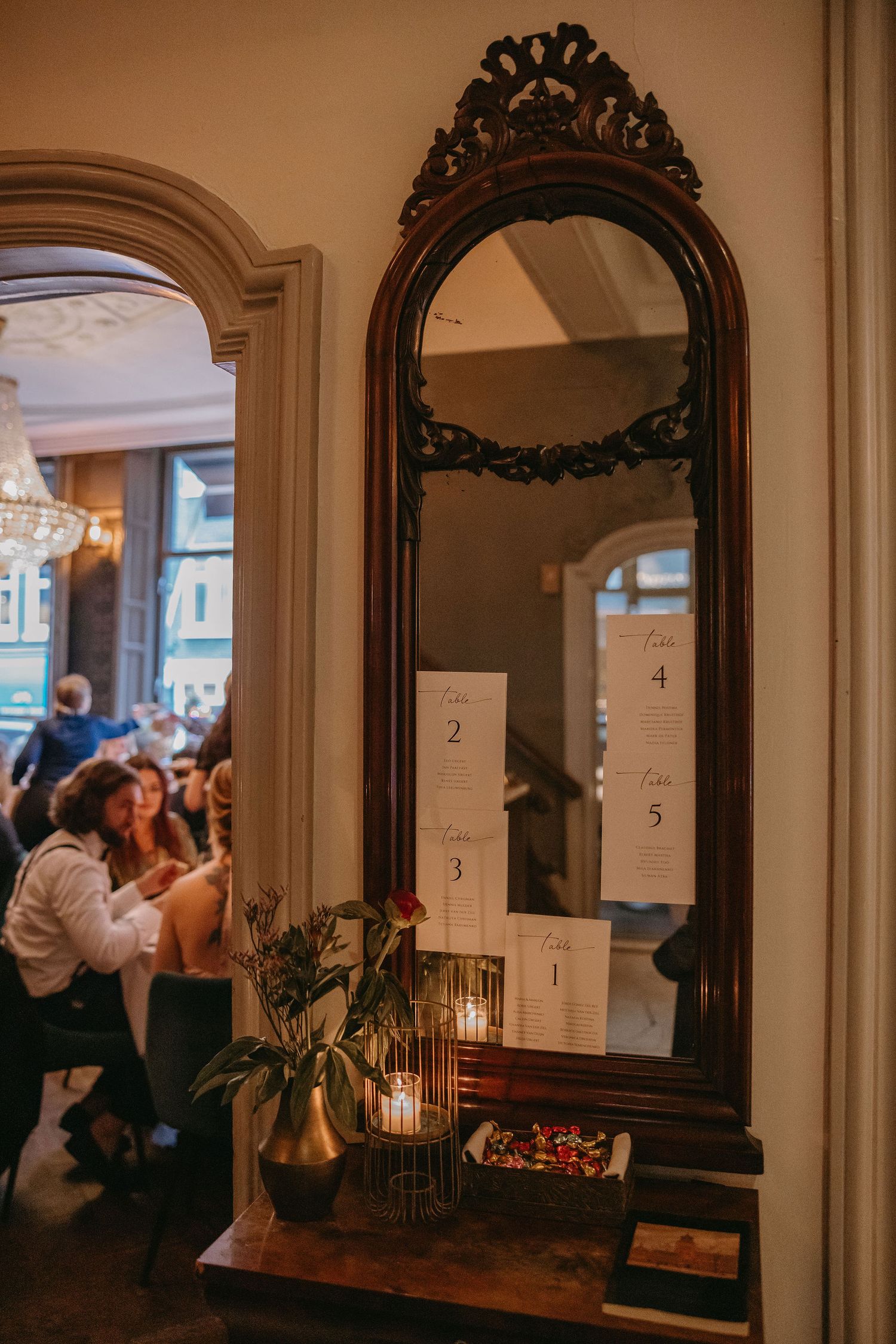 Vintage-style mirrors decorated with candles and wedding reception seating charts.