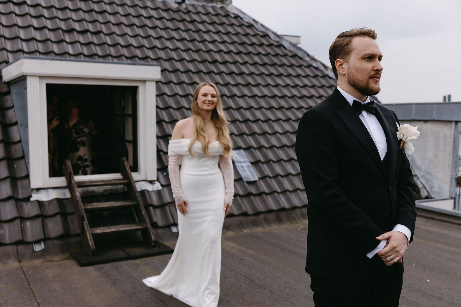 First look moment between bride and groom on a rooftop with grey tiled background.