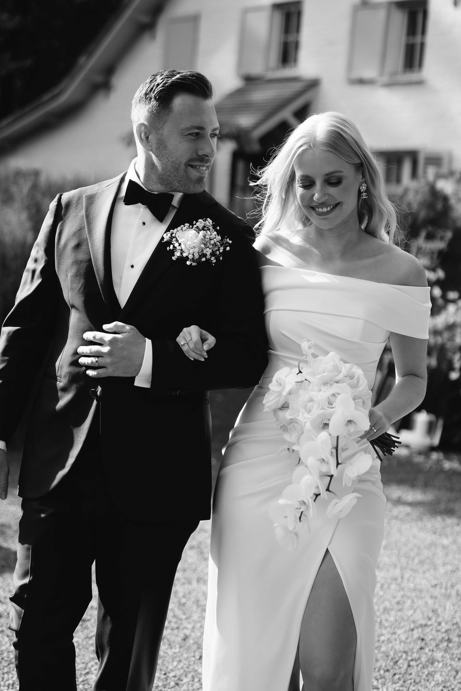 Black and white photo of newlyweds walking together and smiling outdoors.