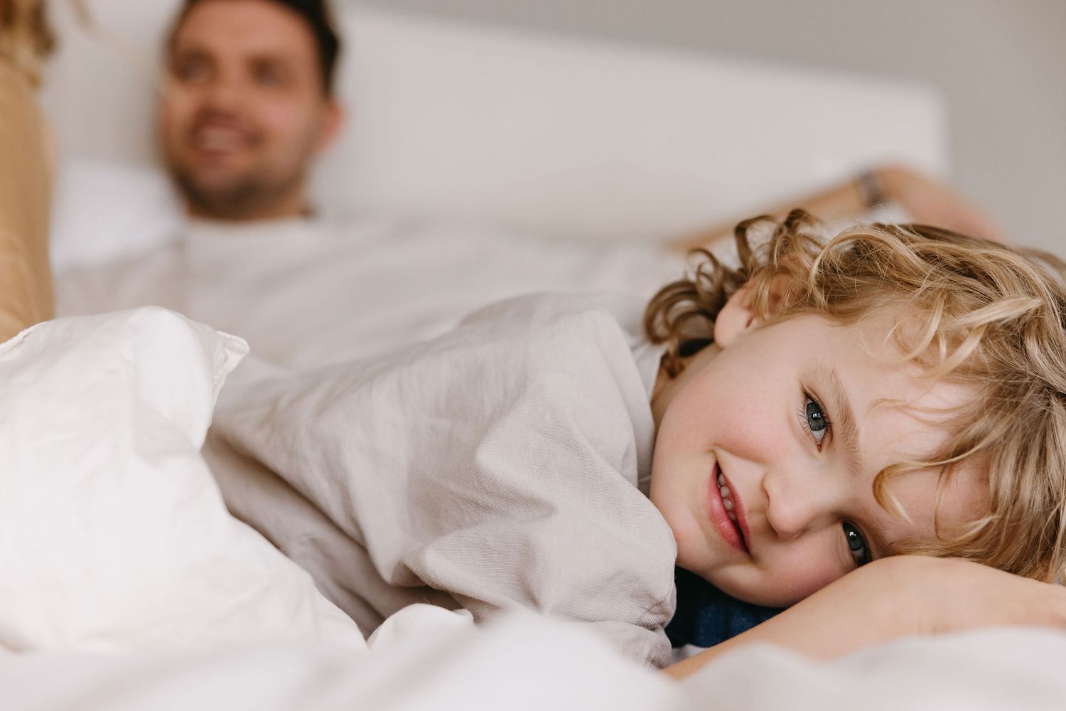 Cozy morning scene with a child resting in white bedding.