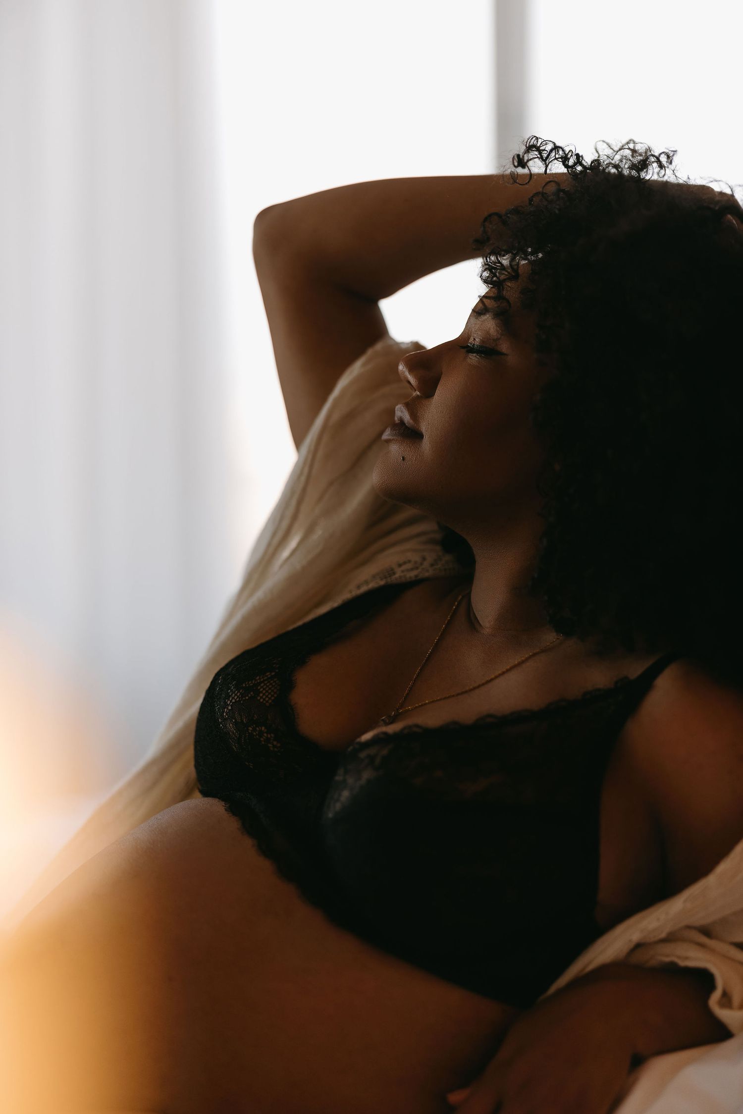Intimate boudoir photography captures a gentle moment in soft morning light.