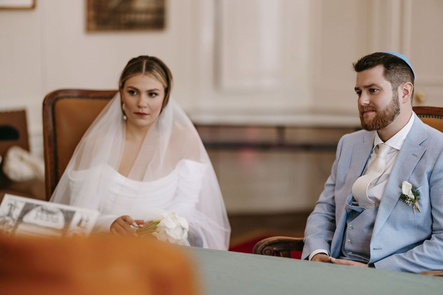 Couple seated at table during wedding reception in formal attire.