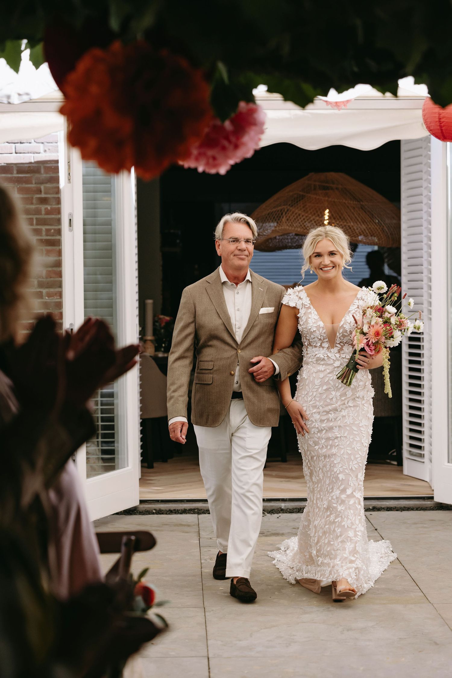 Wedding couple walking together on a white porch with classic shutters.