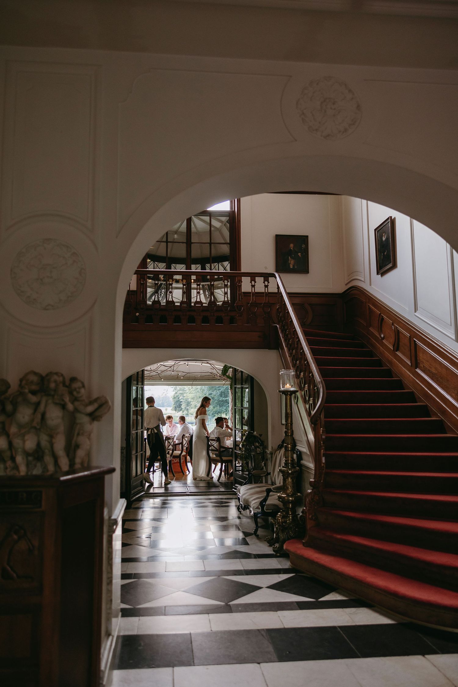 A sequence of dimly lit indoor corridor views with red carpeted staircases and ornate architectural details along the walls.