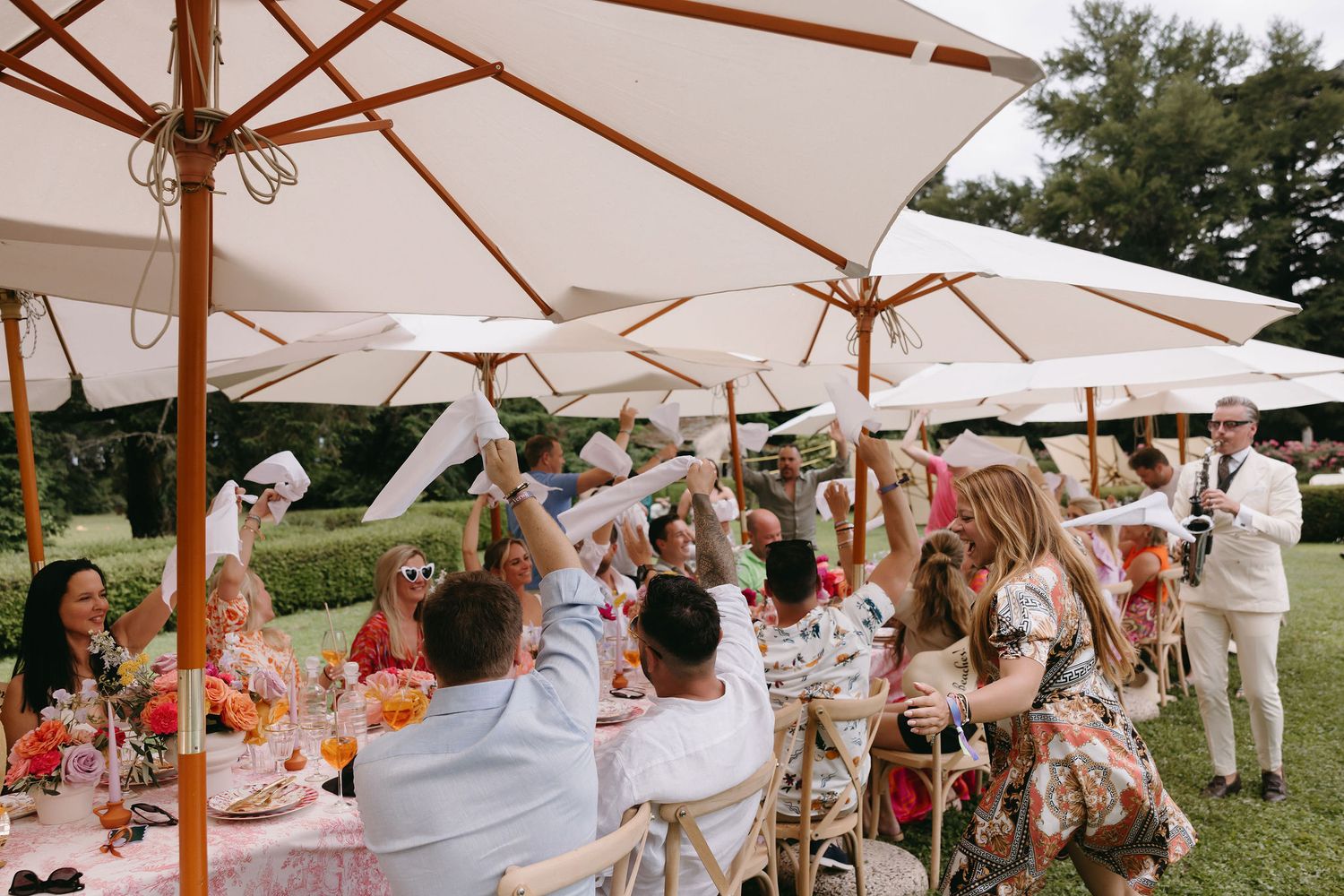 Outdoor wedding celebration with guests dining under white umbrellas.
