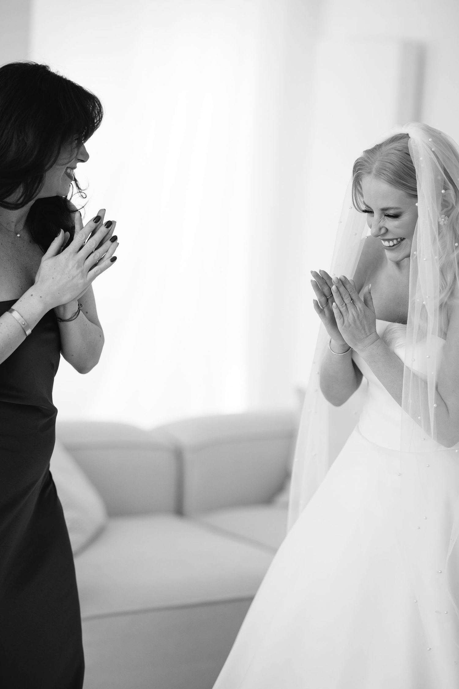 Black and white candid moment of joyful celebration in bridal suite.