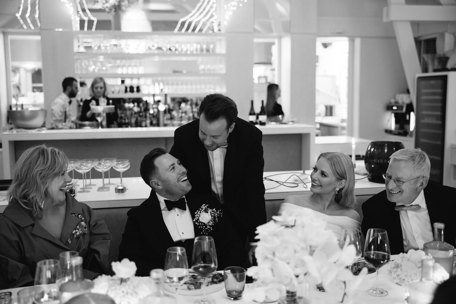 Wedding reception guests enjoying dinner service at an elegant white-tablecloth restaurant.