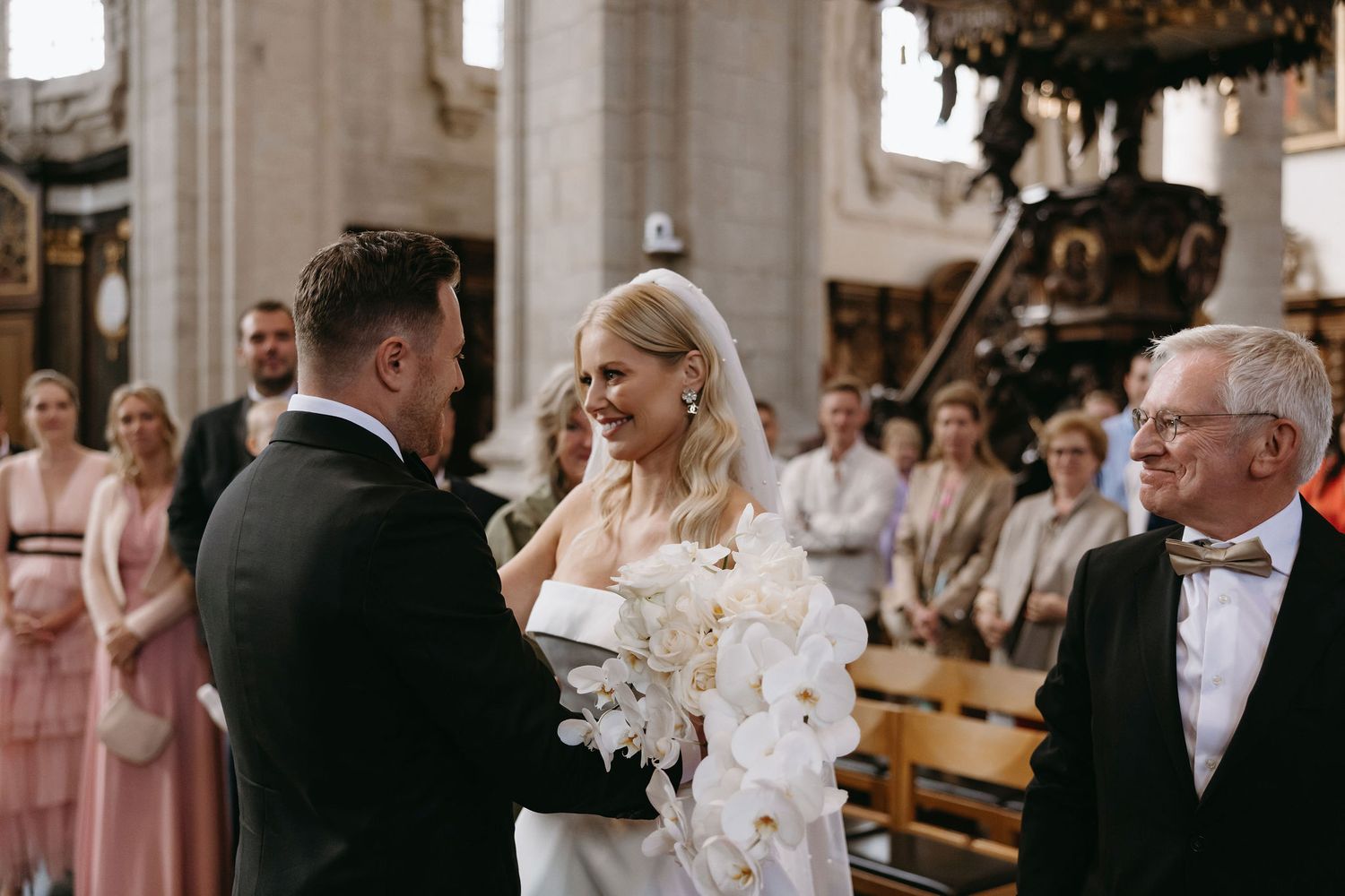 Traditional wedding ceremony taking place in grand cathedral with stone columns.