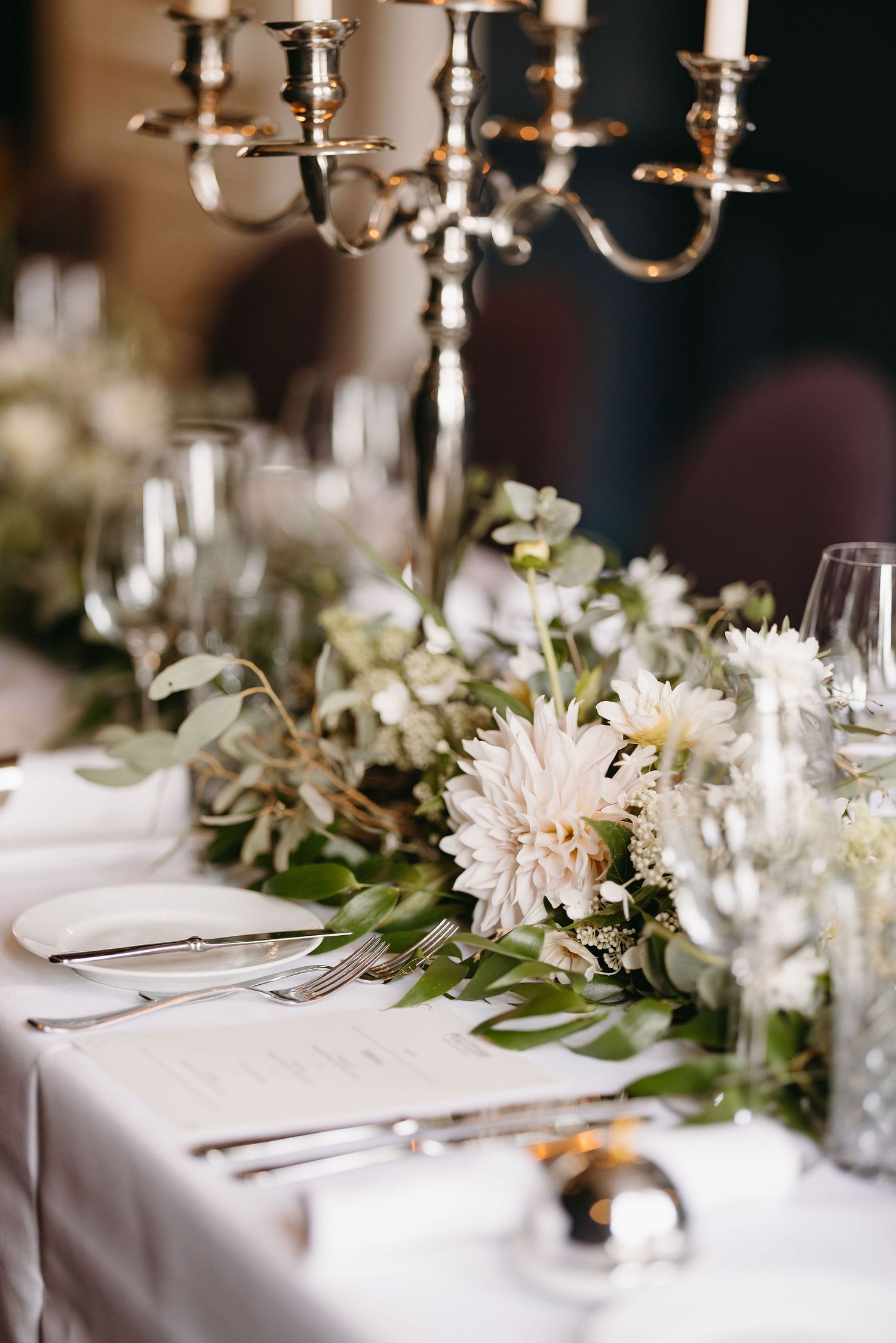 Elegant wedding table setting with white flowers, candelabras and place settings.