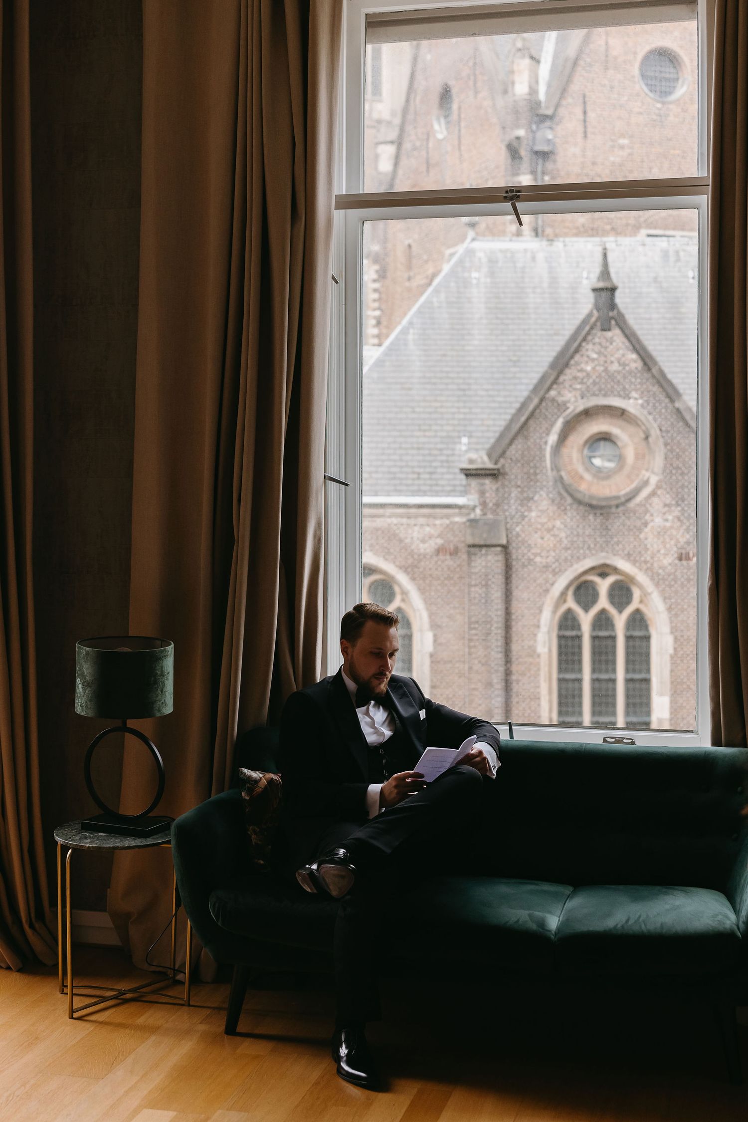 Interior view of a historic church window with green velvet couch and vintage decor.