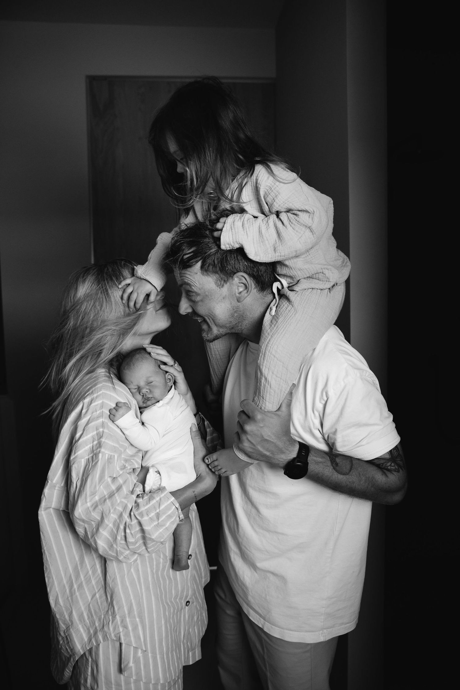 A joyful black and white family portrait showing parents and children sharing an intimate moment.