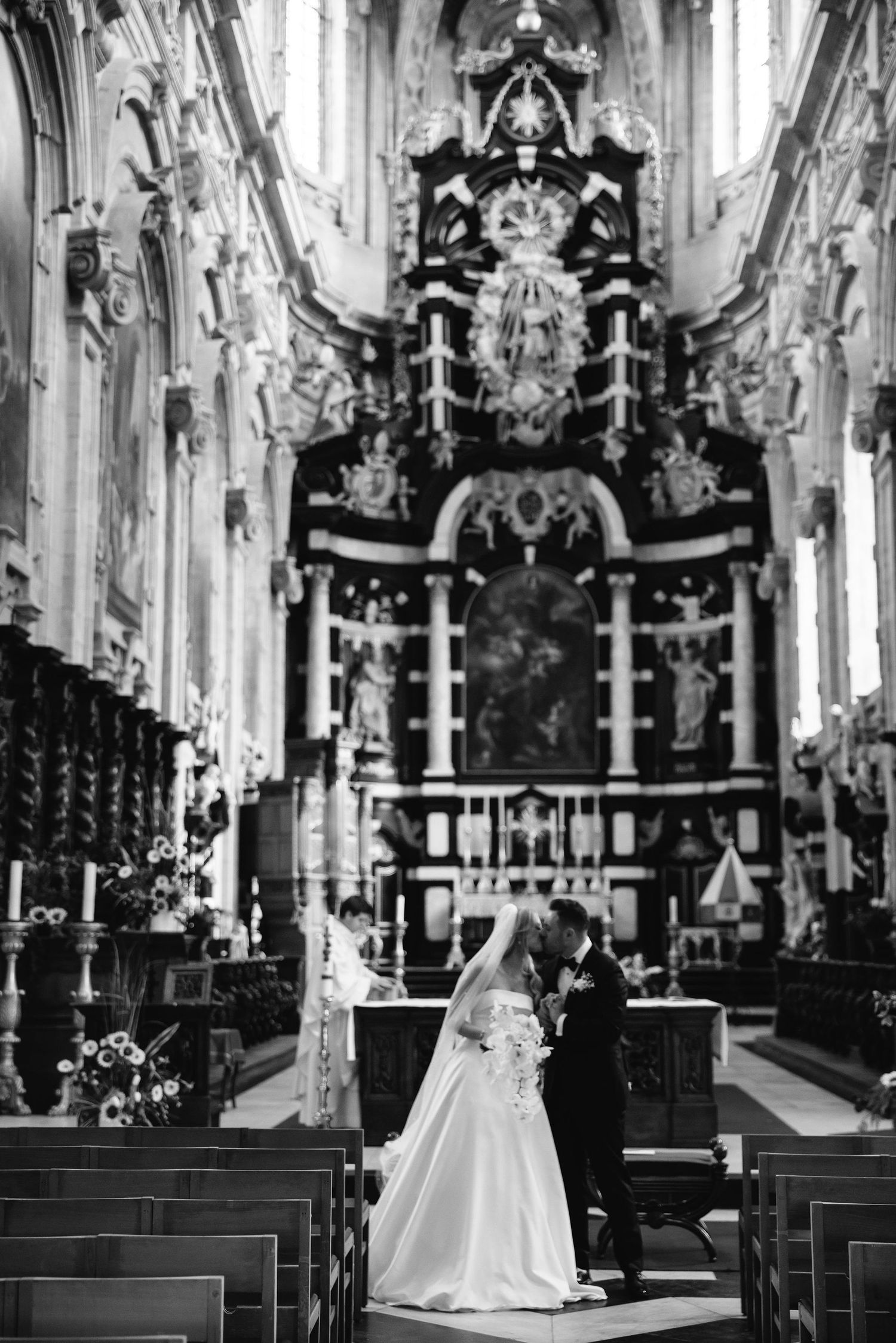 A wedding ceremony in a grand cathedral with ornate baroque altar and architecture.