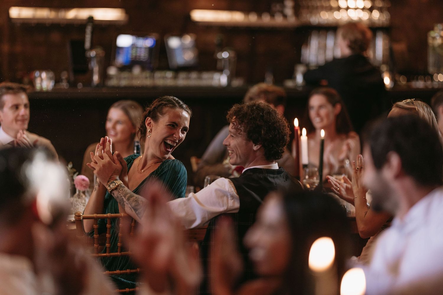 Wedding reception celebration with guests gathered in a dimly lit indoor venue.