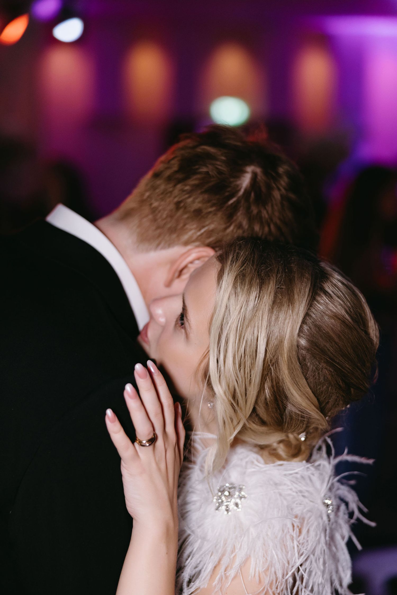 Intimate dance moment captured under purple mood lighting at wedding reception.