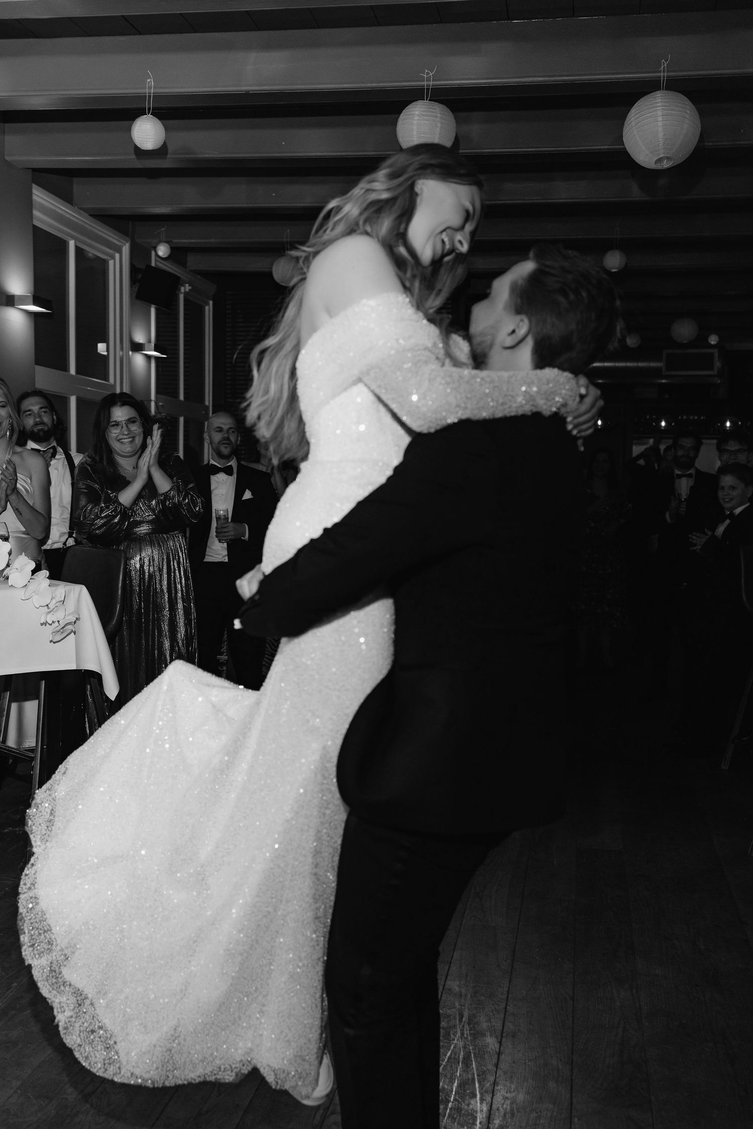 A dramatic first dance moment at a wedding reception with hanging paper lanterns in the background.