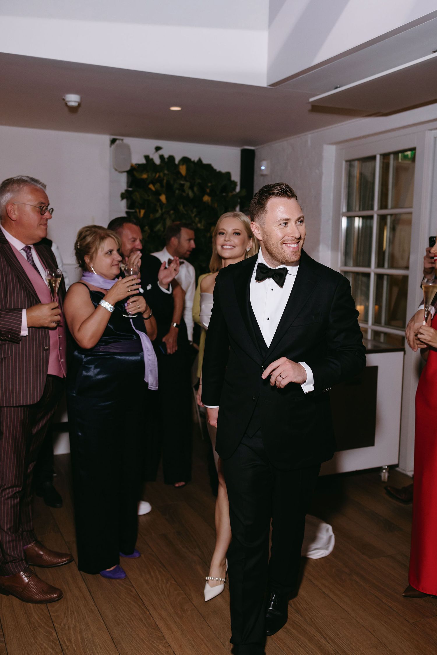 Wedding guests dance and celebrate on a wooden dance floor during an evening reception.