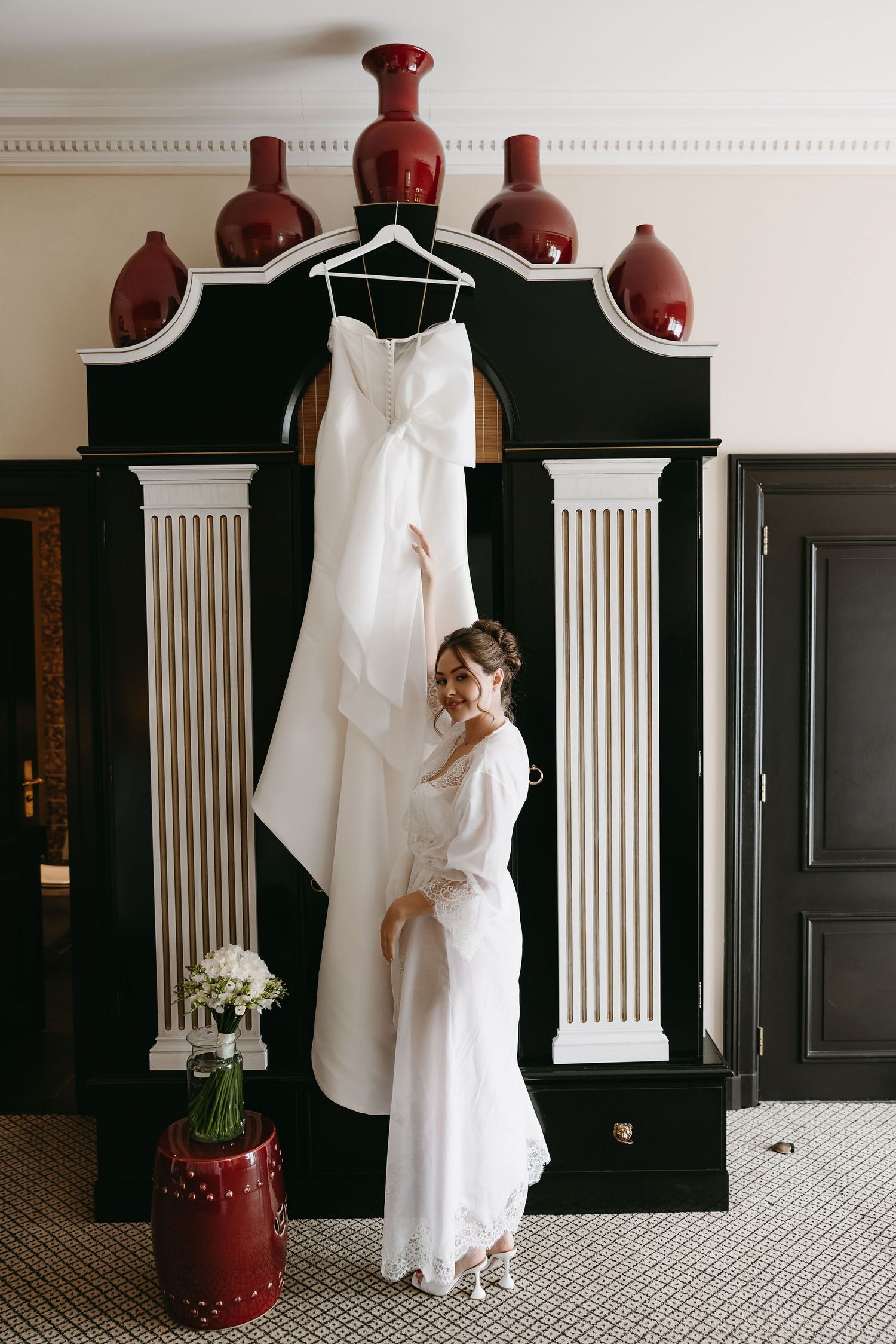 A series of elegant wedding dress detail shots in black and white showing the gown hanging against a dark wood wardrobe.