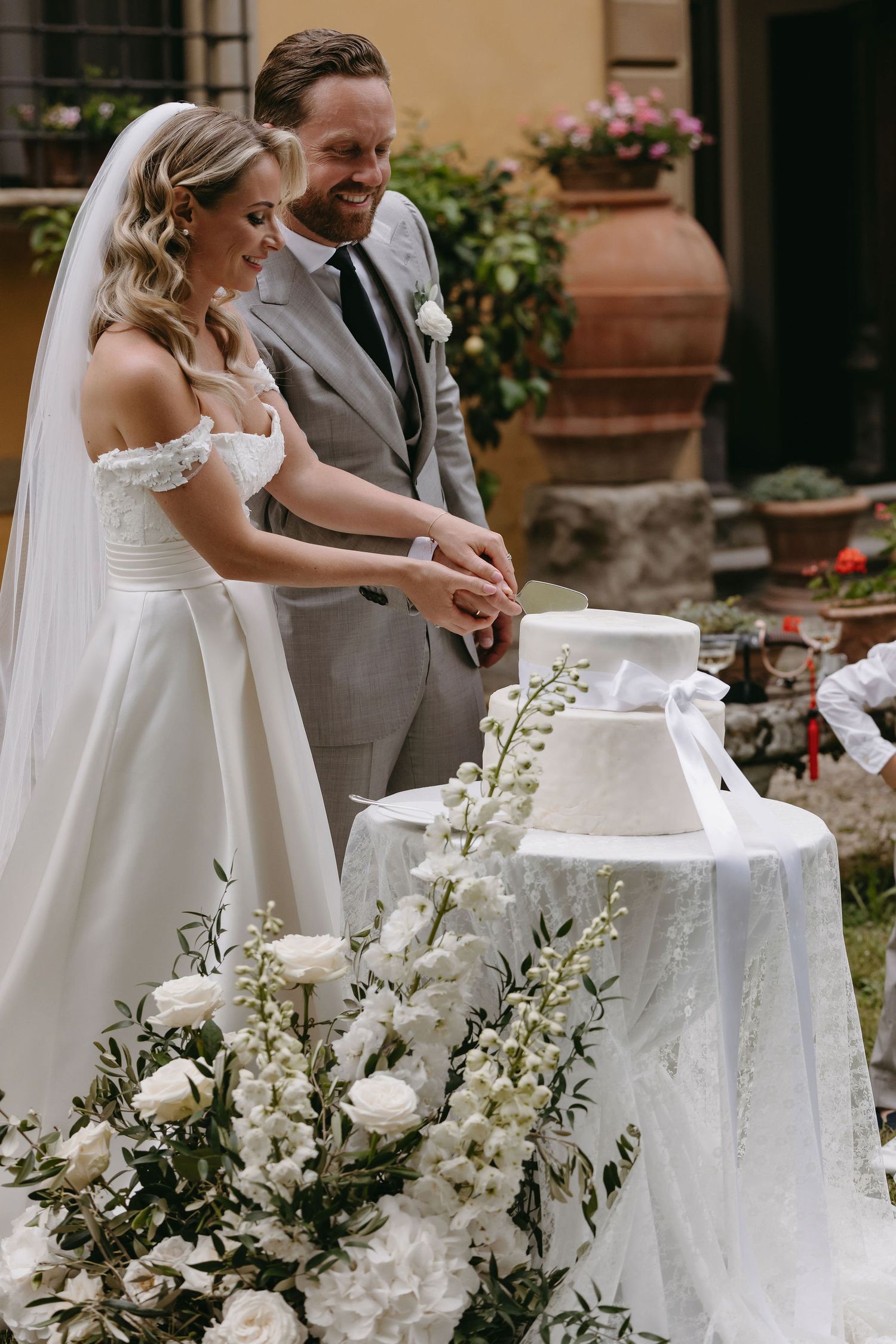 A wedding cake cutting moment surrounded by elegant white floral decorations.