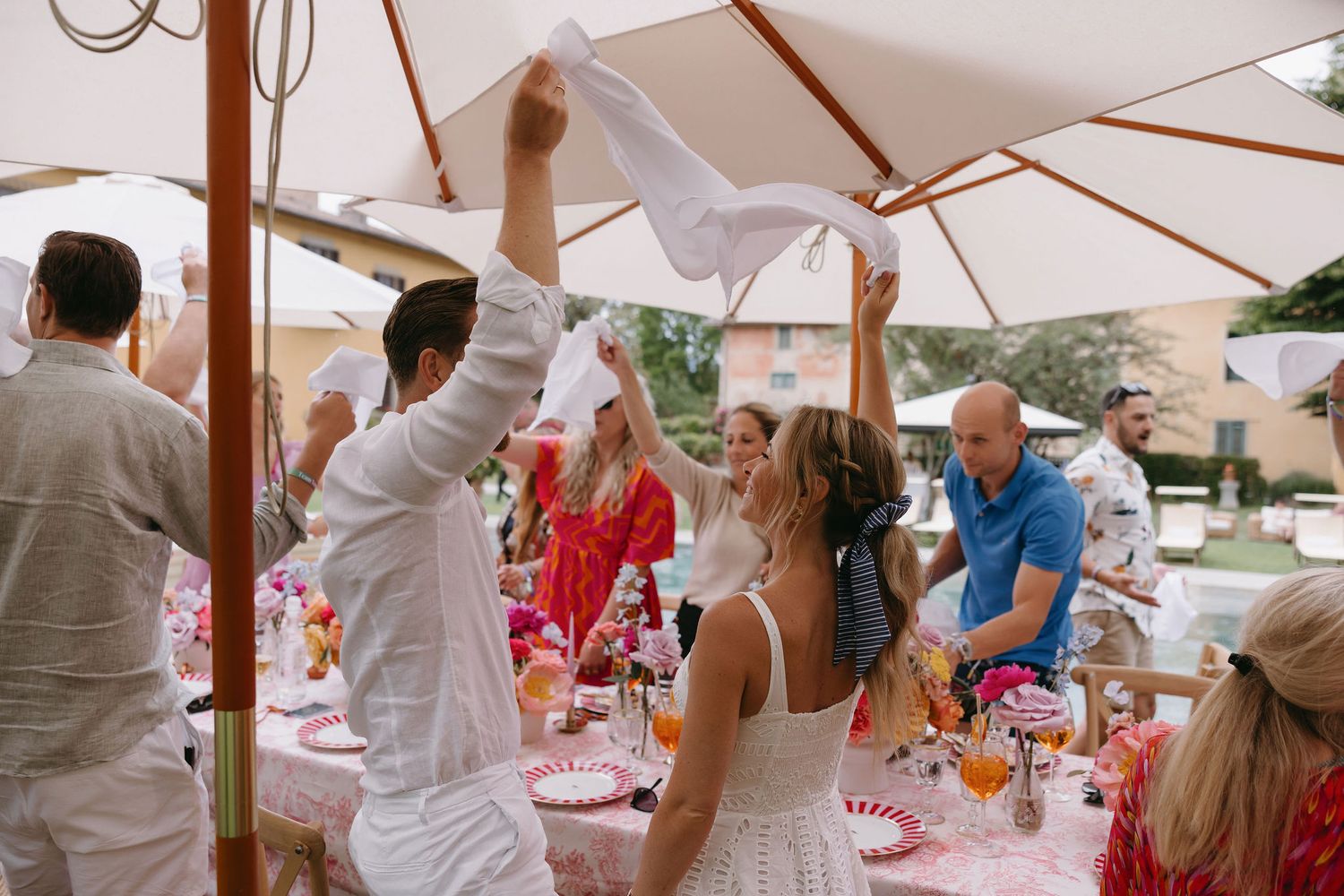 Wedding guests celebrating under a white tent during an outdoor reception.