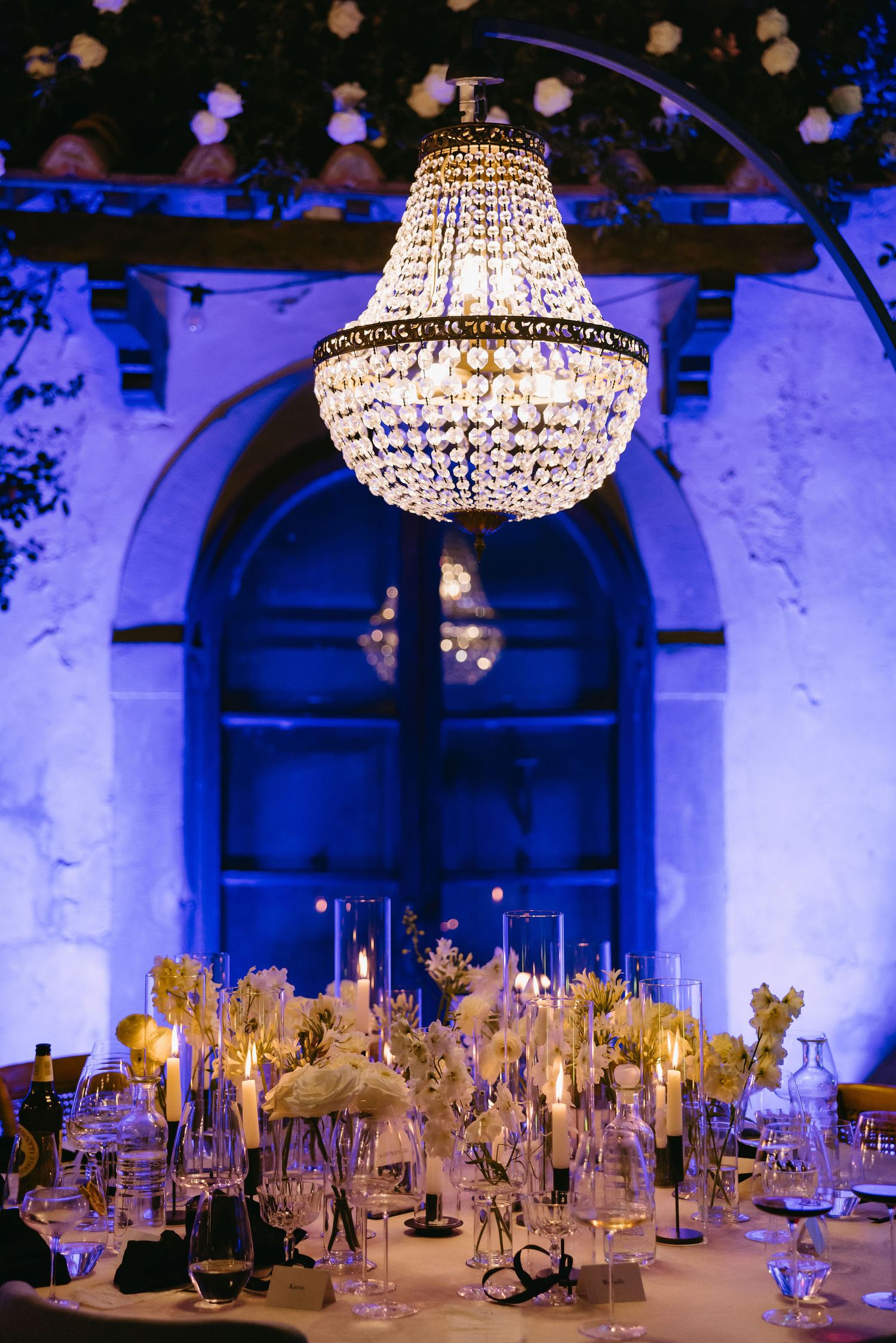 Crystal chandelier hanging over an elegantly decorated wedding reception table.