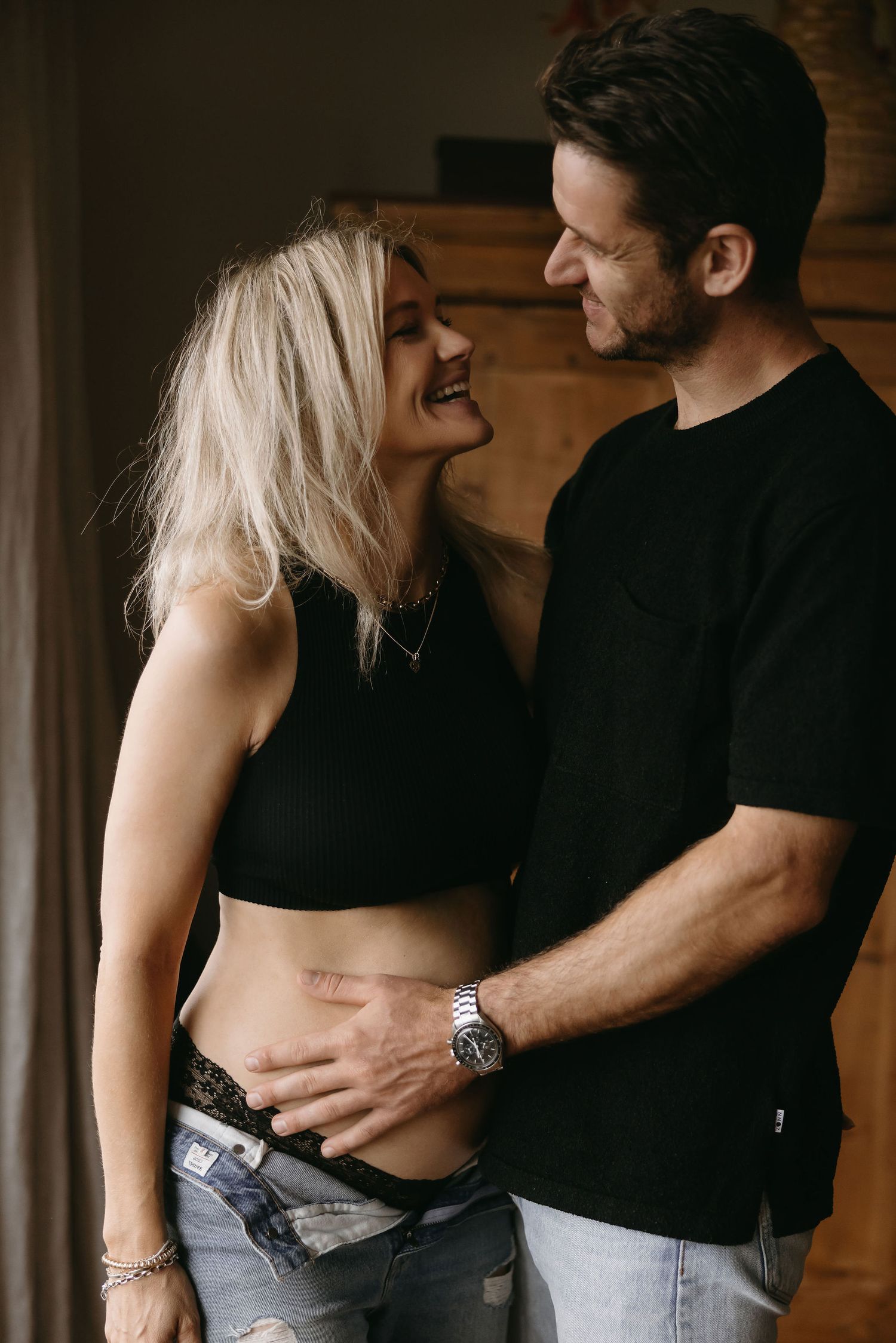 Intimate couple photography session with casual denim and black clothing indoors.