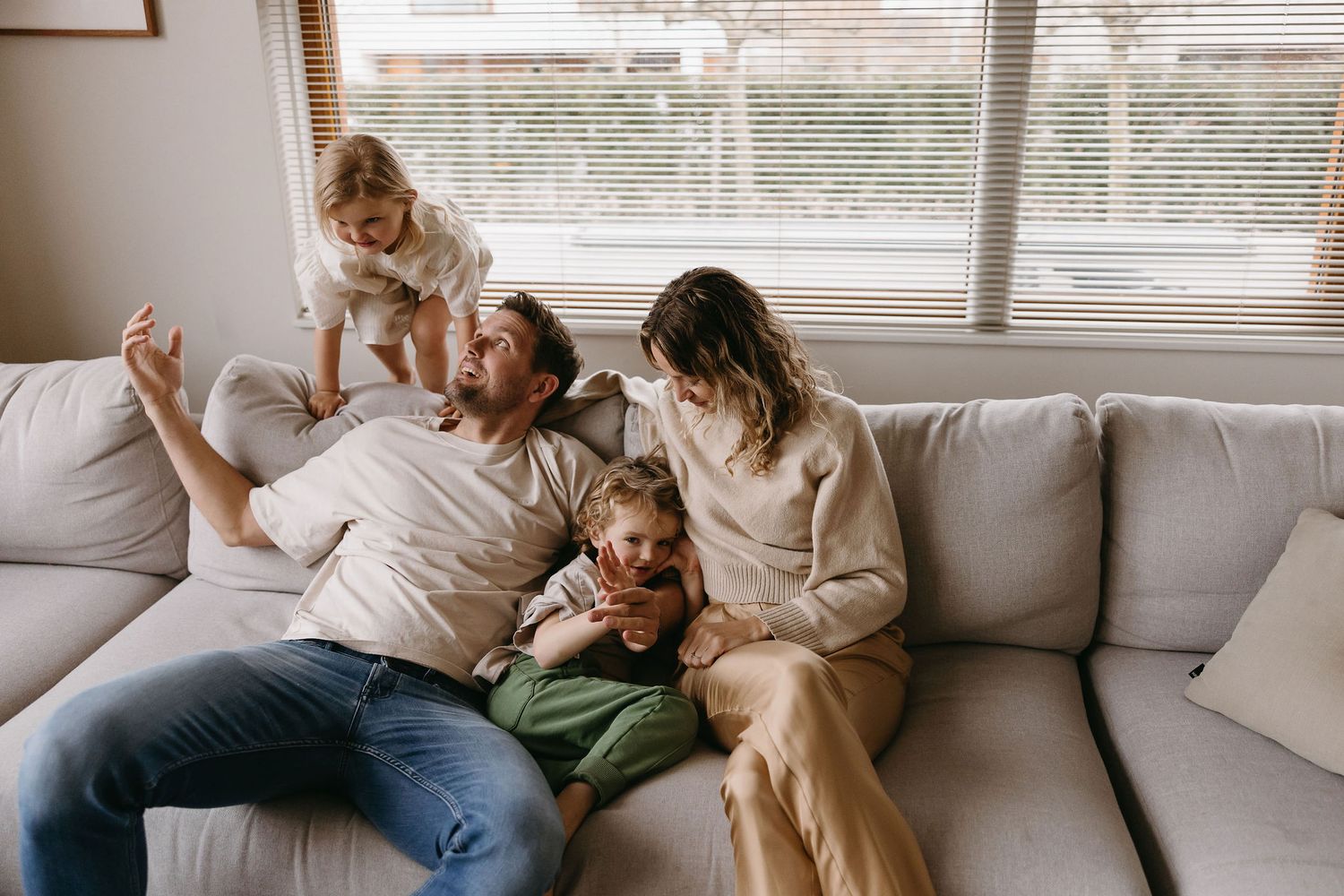 Family sharing tender moments together on a comfortable couch by window light.