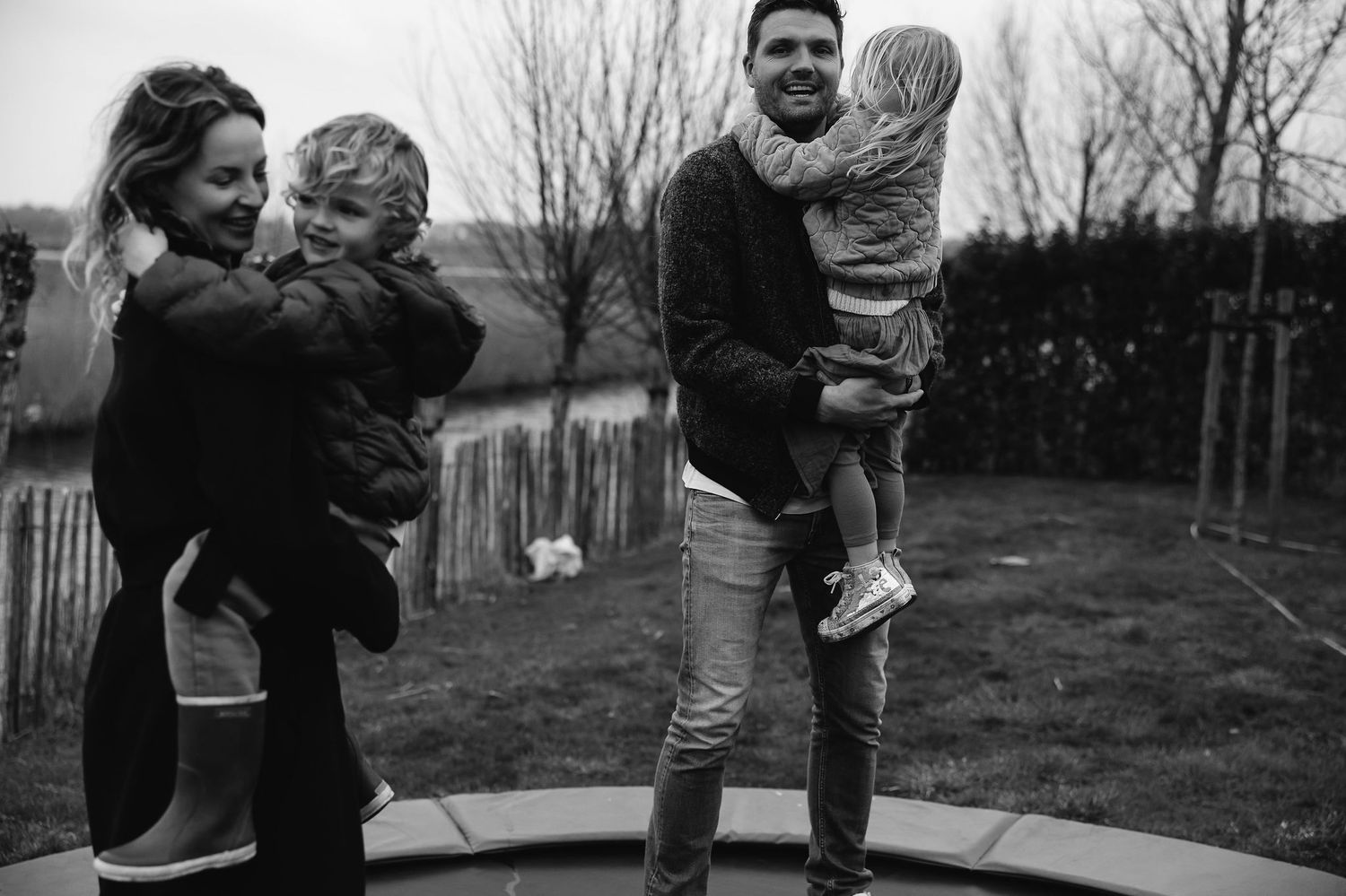 A family enjoying time together while jumping on a trampoline in their backyard.