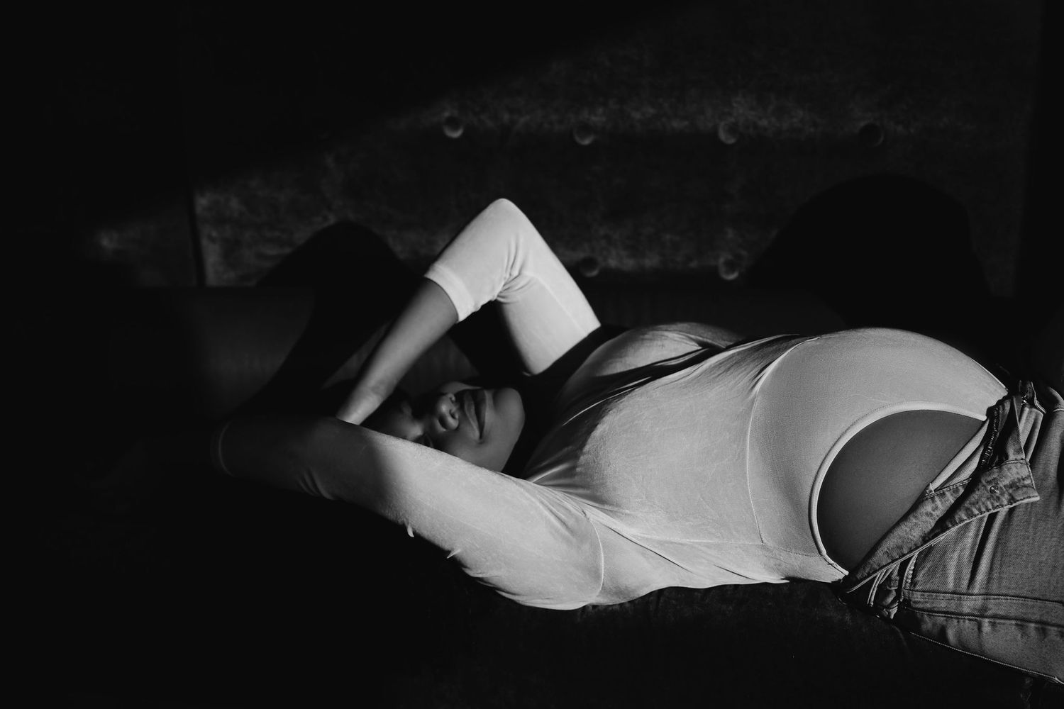 Intimate black and white portrait in minimalist setting with dramatic lighting.