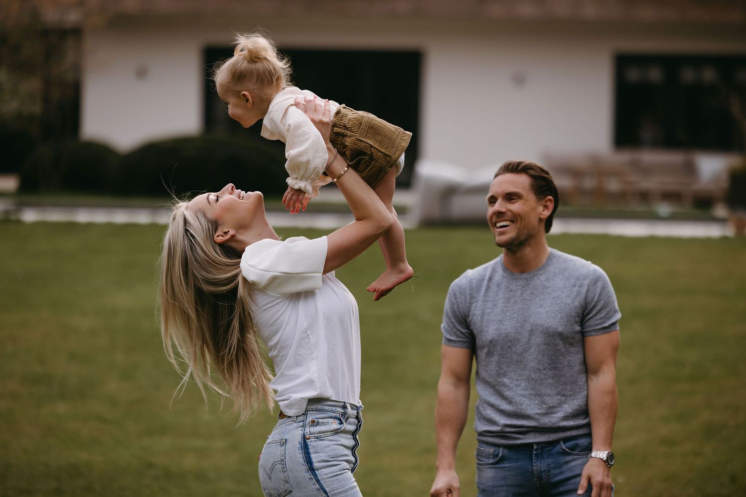 Family sharing playful outdoor moments in casual wear on grassy field.