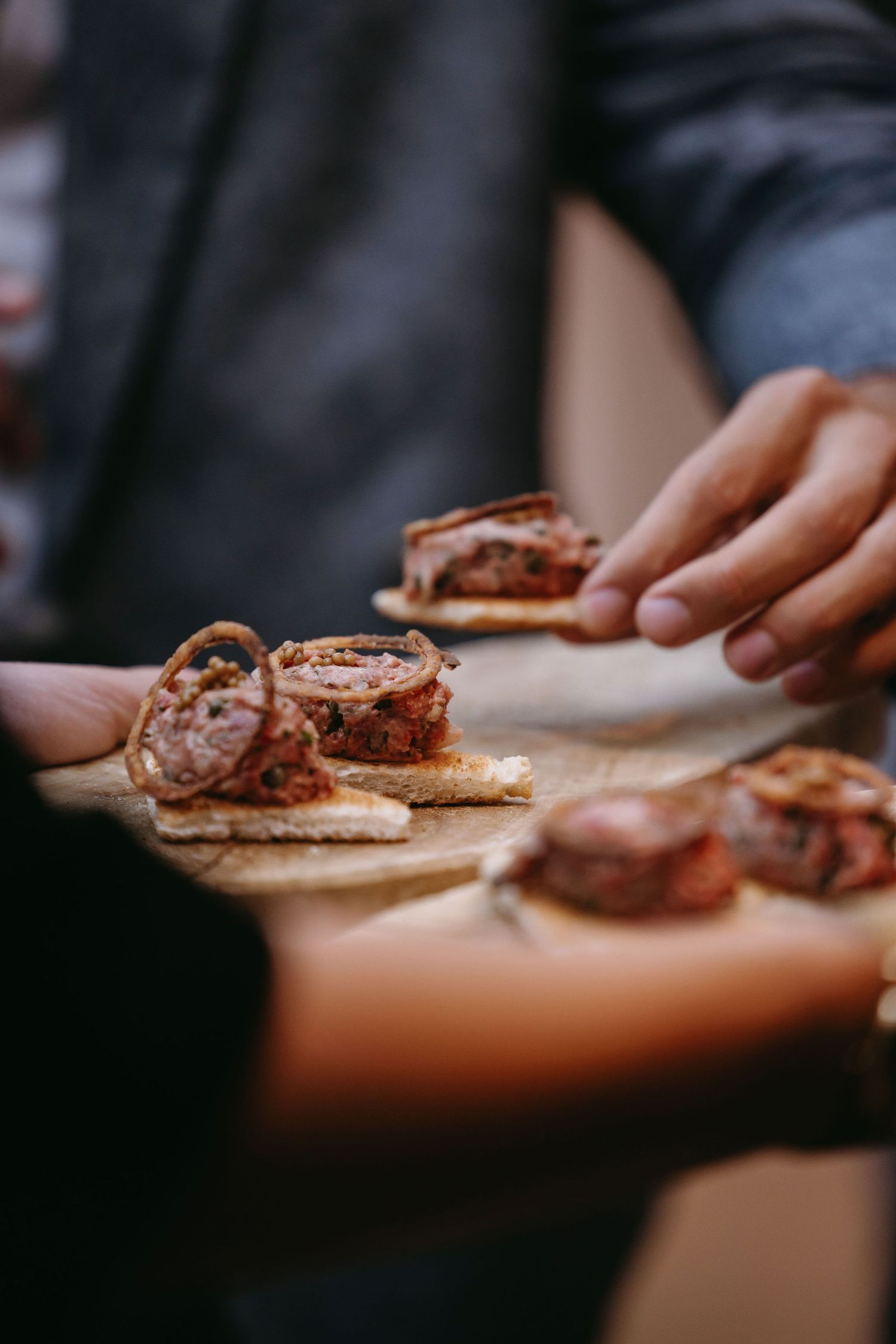 Close-up of appetizers being served on wooden board at wedding reception.