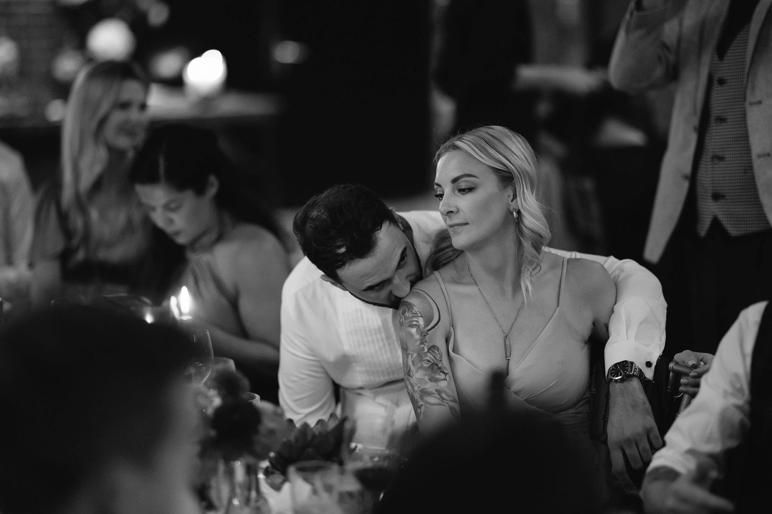 Intimate candlelit moment captured during wedding reception in black and white.