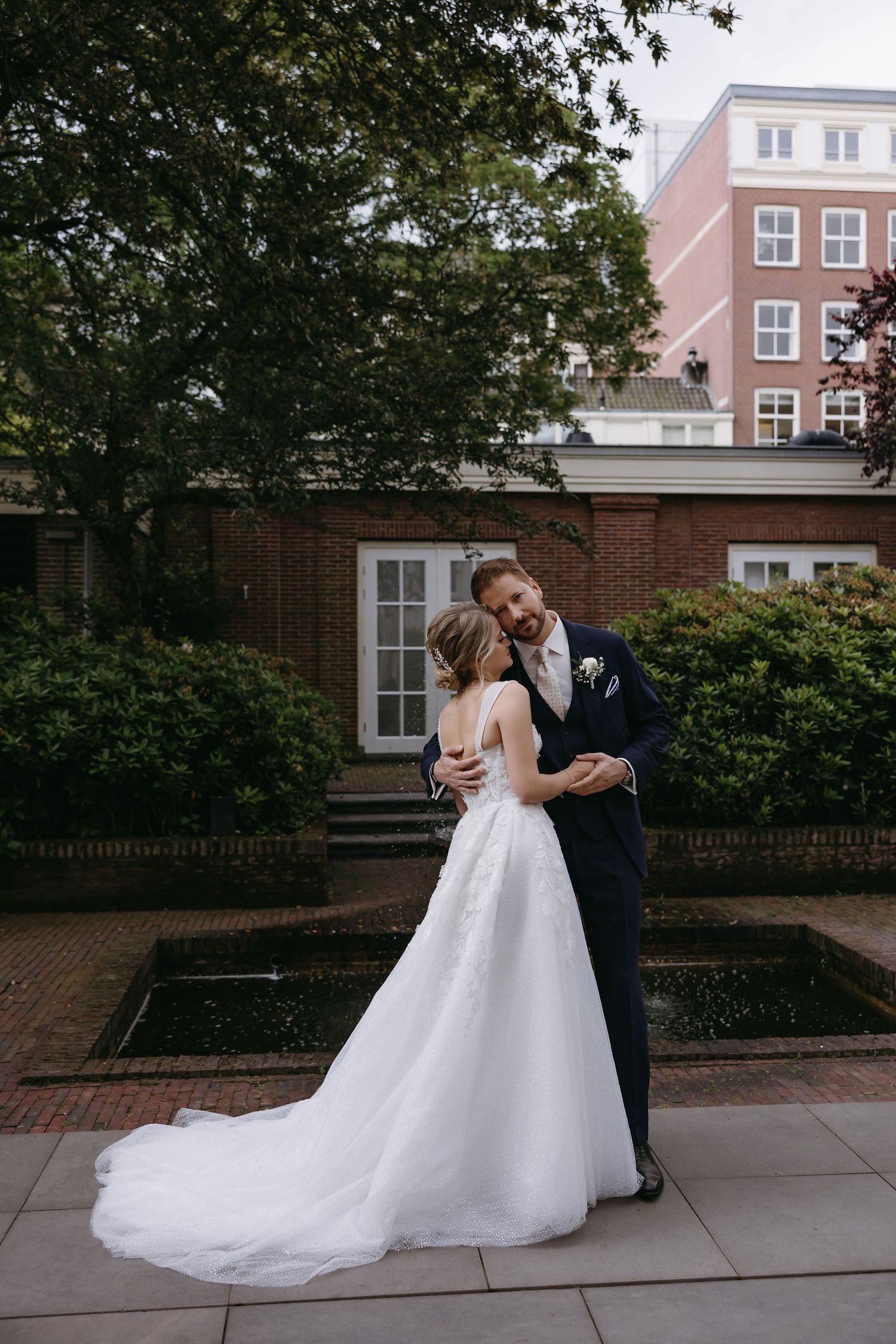 Elegant couple dancing together on a brick-lined sidewalk in wedding attire.