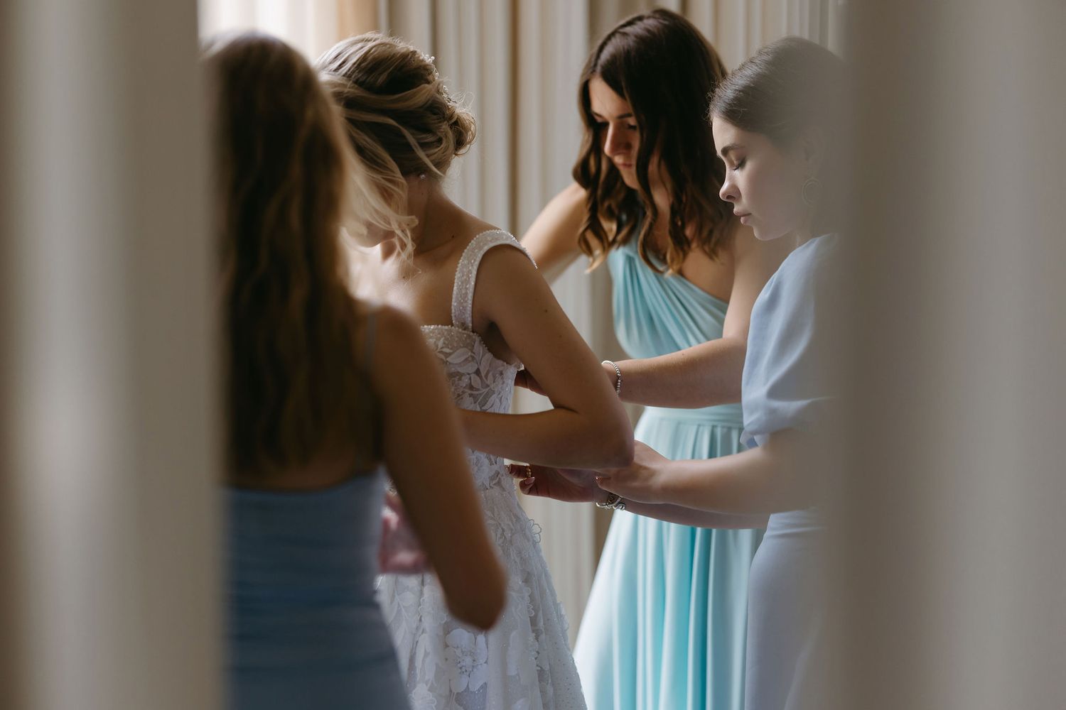 Makeup artist applying finishing touches to bride's face during wedding preparation.