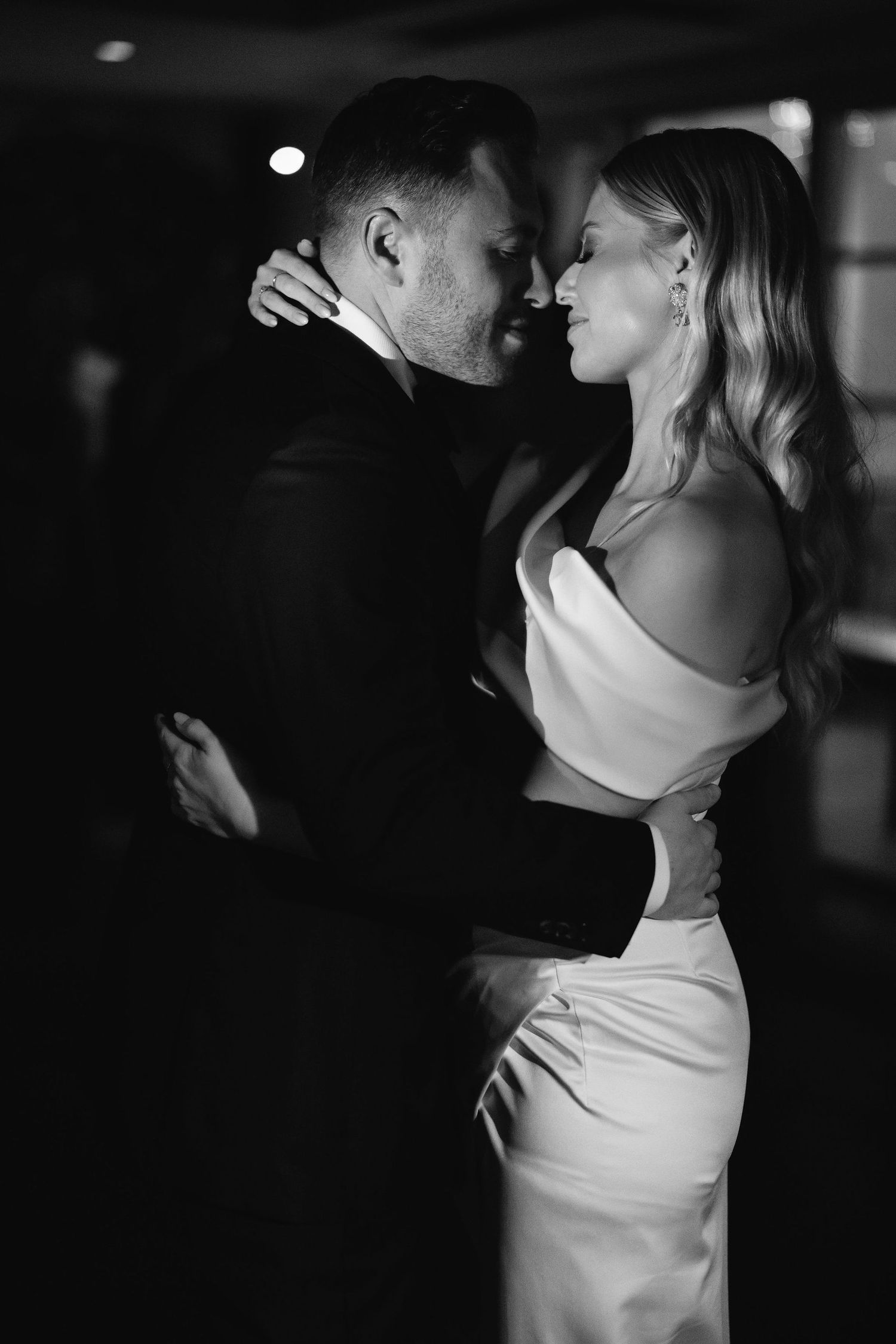 Romantic black and white photos of a couple embracing during what appears to be a wedding dance.