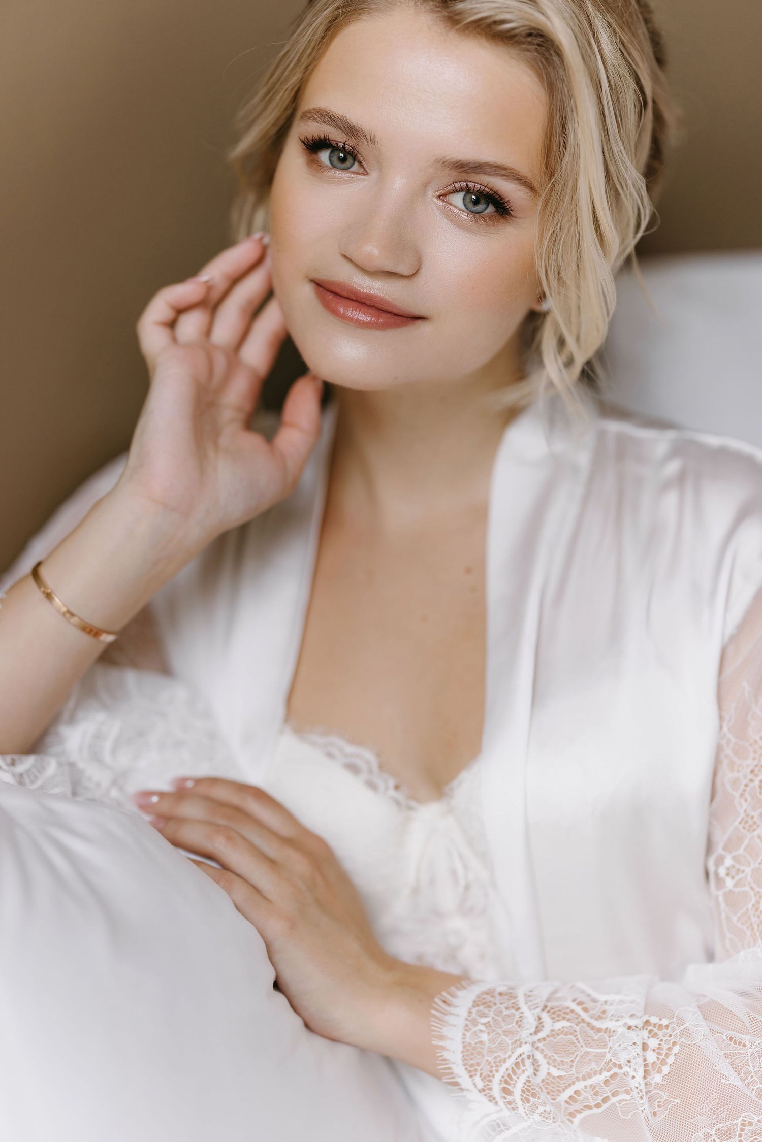 Woman in white lace robe poses during wedding day preparations.