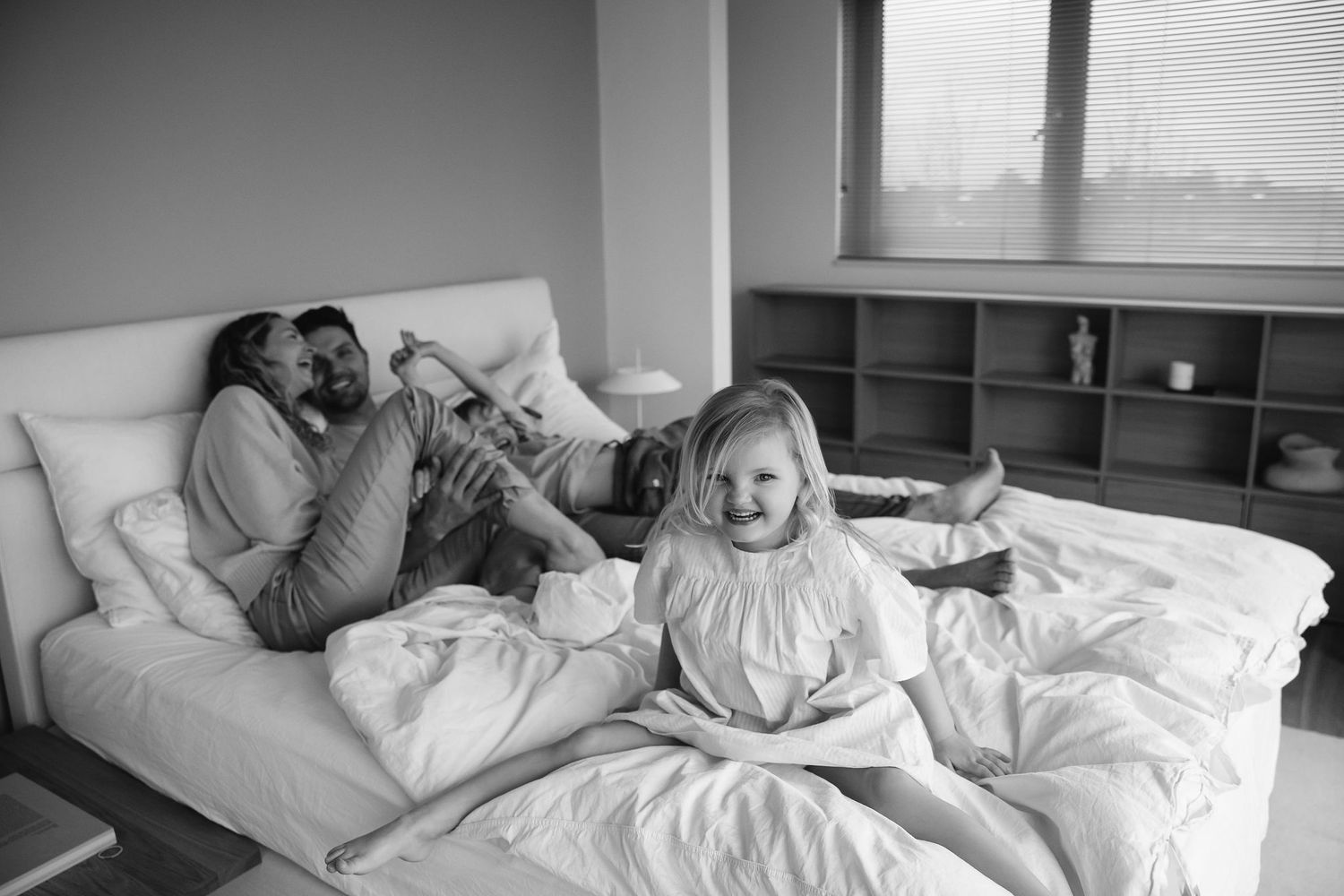Series of intimate black and white photographs showing family relaxing in bed.
