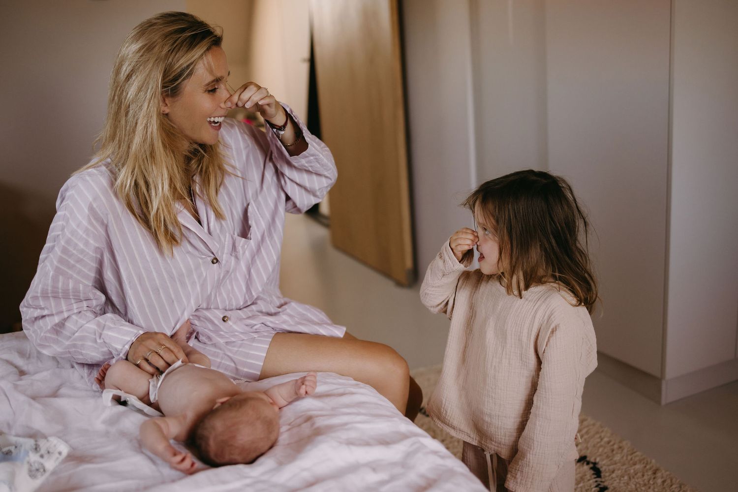 Candid lifestyle photo of family sharing playful moment on bed.