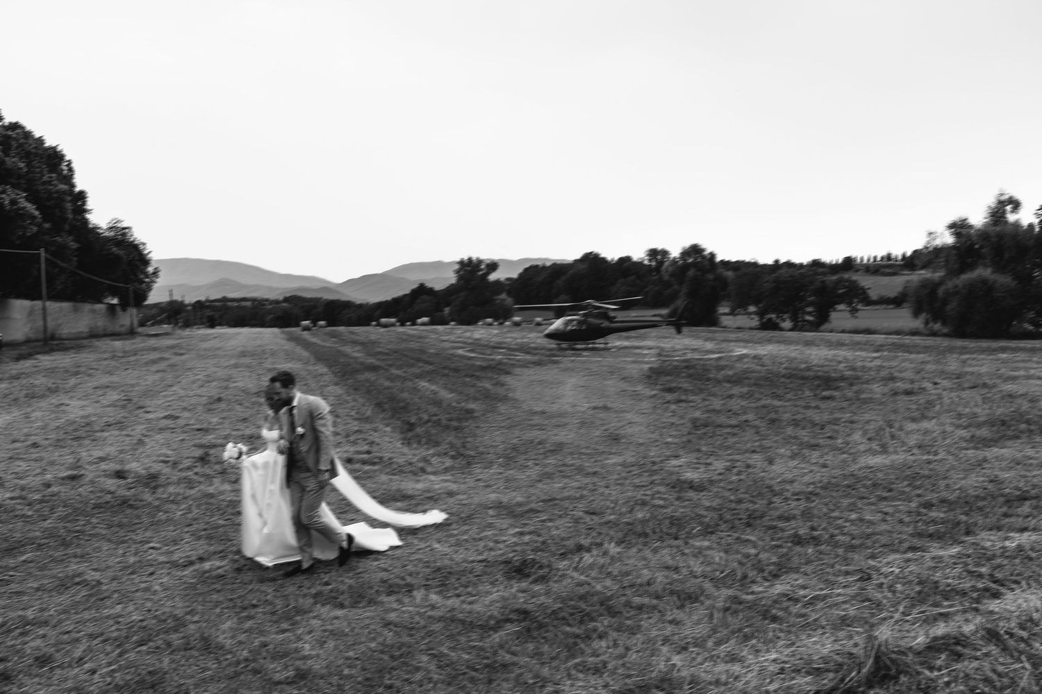 Black and white landscape photograph of a couple sitting in a vast field.