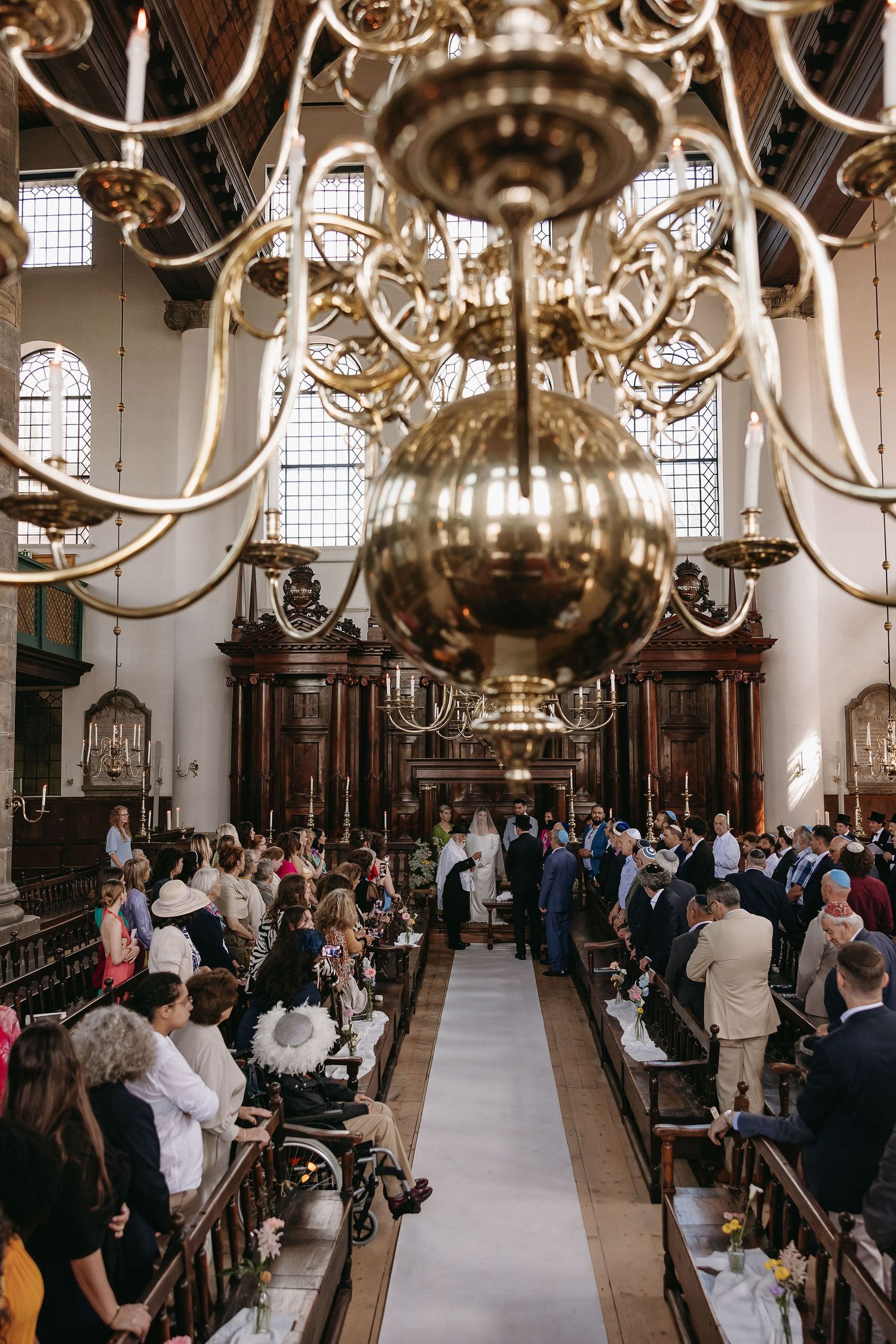 A grand church interior with massive chandelier and guests seated for a wedding ceremony.