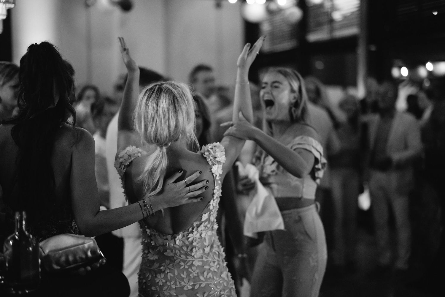 Wedding guests dancing and celebrating on the dance floor at reception.