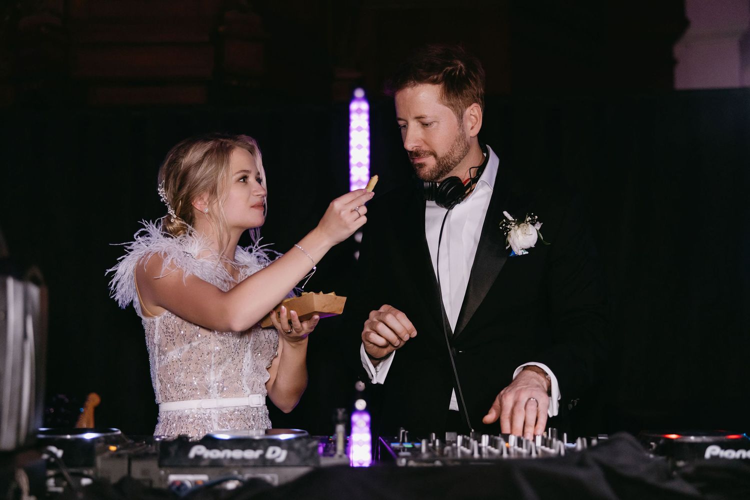 Couple interacting with DJ equipment during wedding reception party.