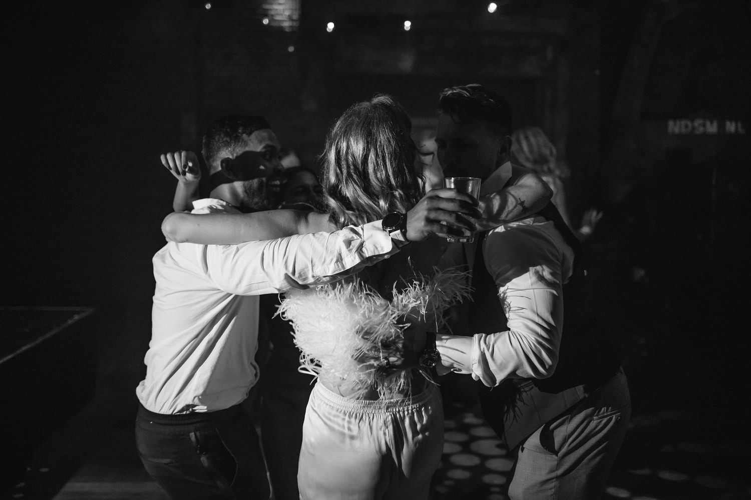 Black and white photo of people embracing in a group hug at a celebration.