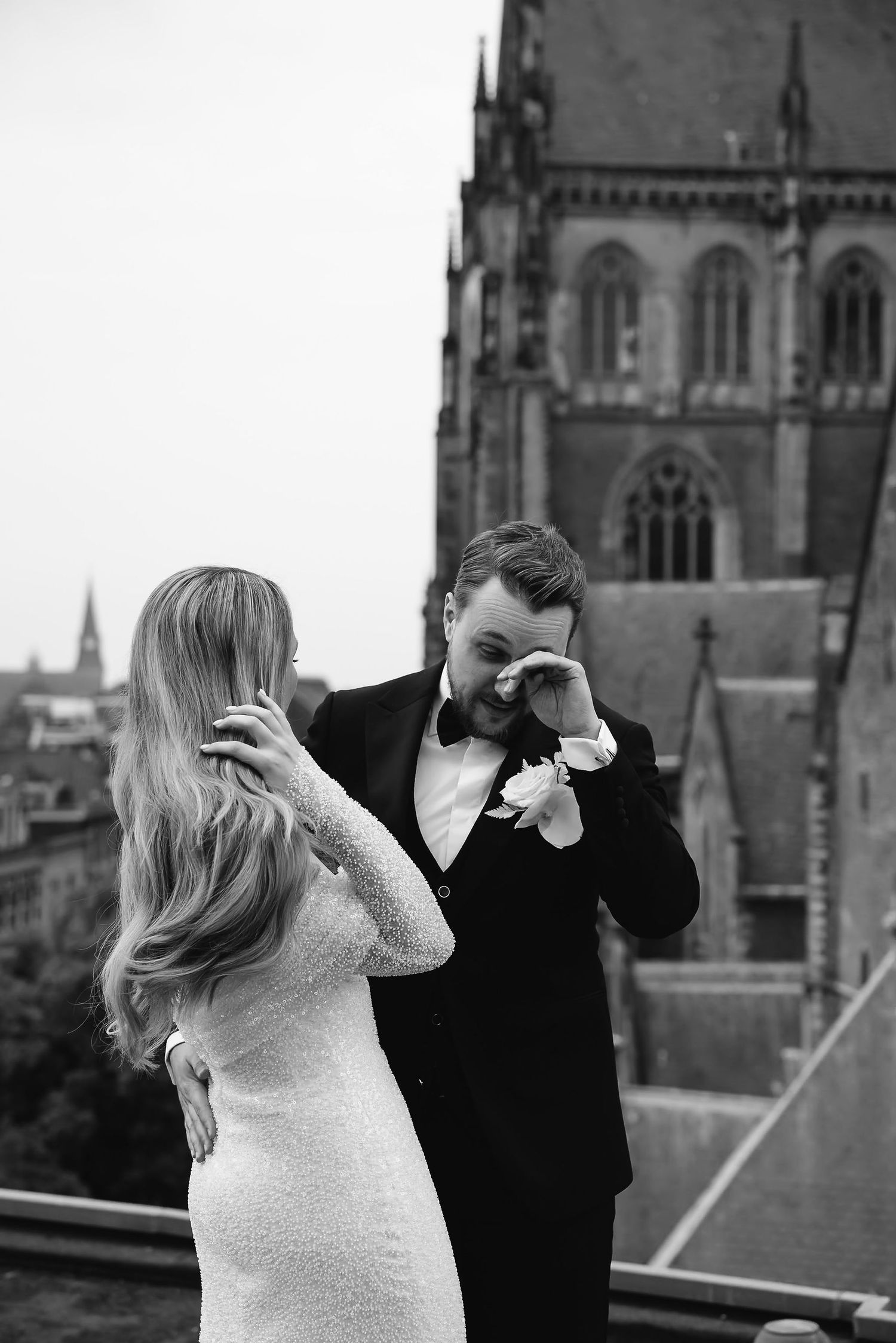 A romantic black and white moment captured with a gothic church spire in the background.