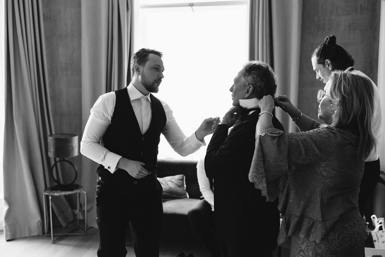 Black and white photo showing wedding party getting ready in elegant formal attire.