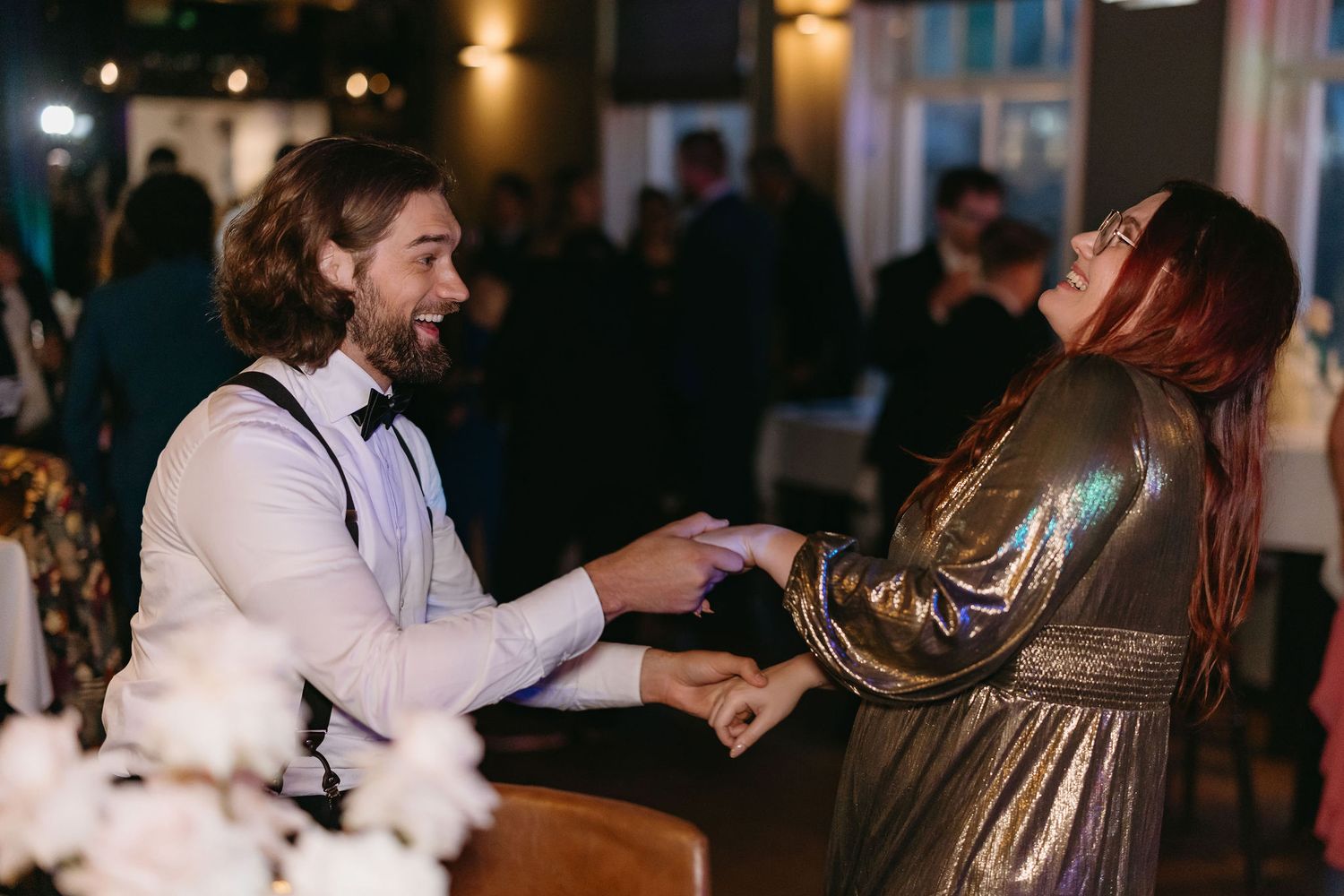 Wedding guests dancing in a dimly lit reception venue.