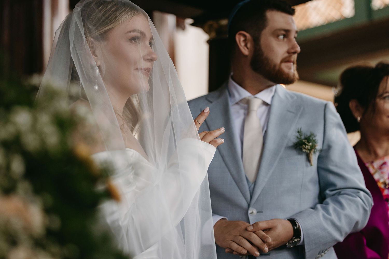 Modern wedding couple in light blue suit and white dress during ceremony.