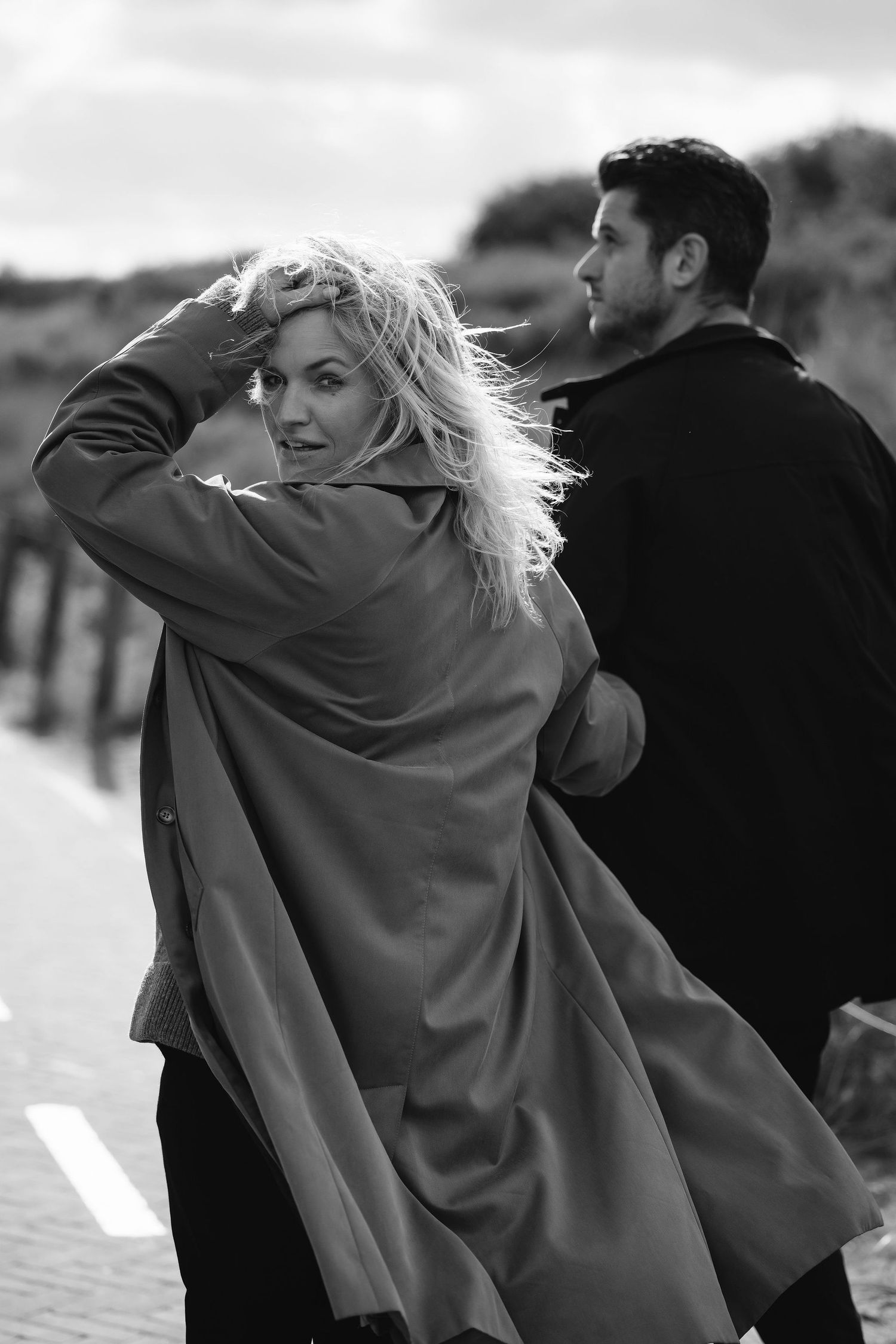 Candid black and white photo of couple outdoors with windswept hair.