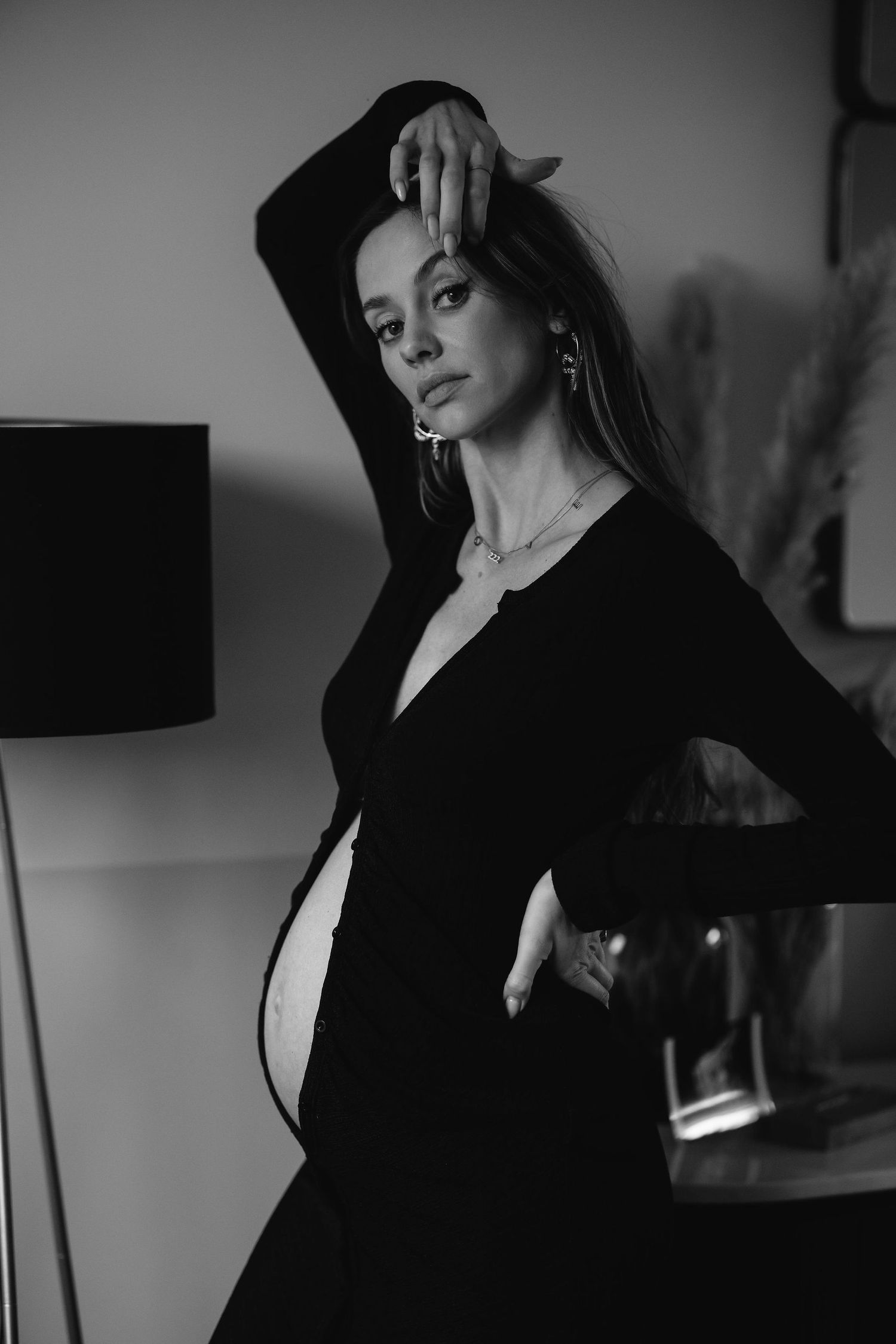 A dramatic black and white portrait showcasing an elegant maternity silhouette against a wall.